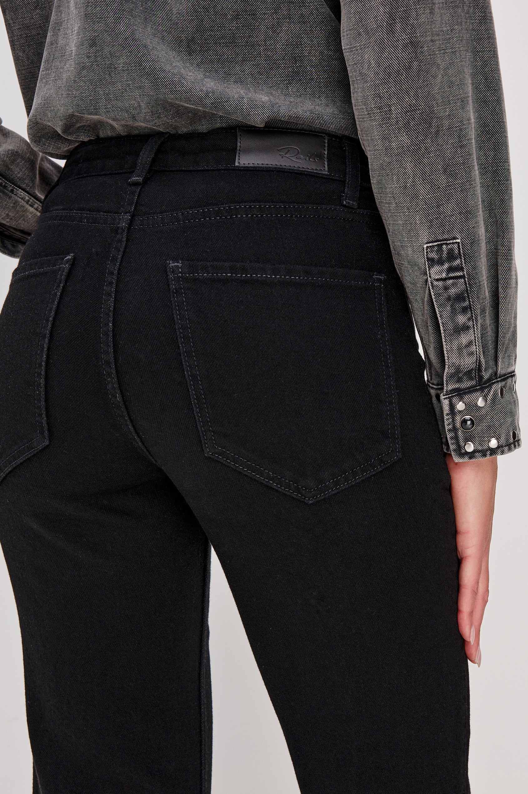 Alamitos is a high waisted denim trouser with flared leg and front patch pockets in Blackout colorway. Back detail view on model.