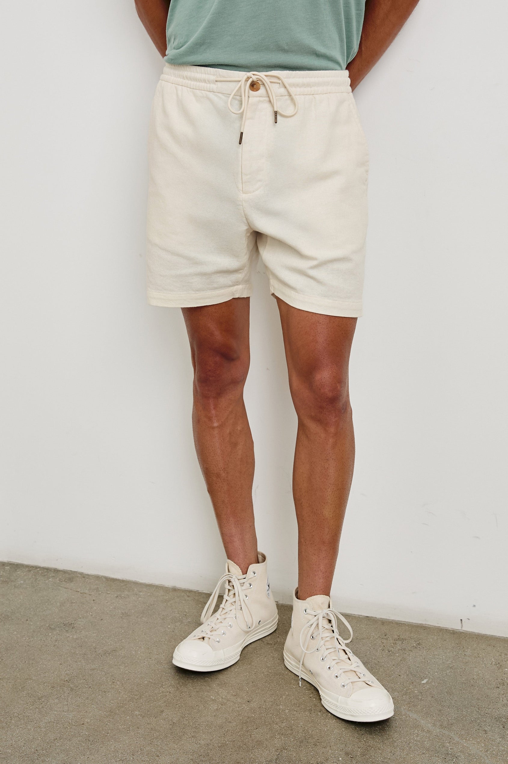 Archer medium length cotton short with adjustable drawstring and front button closure in Ecru - front view on model.
