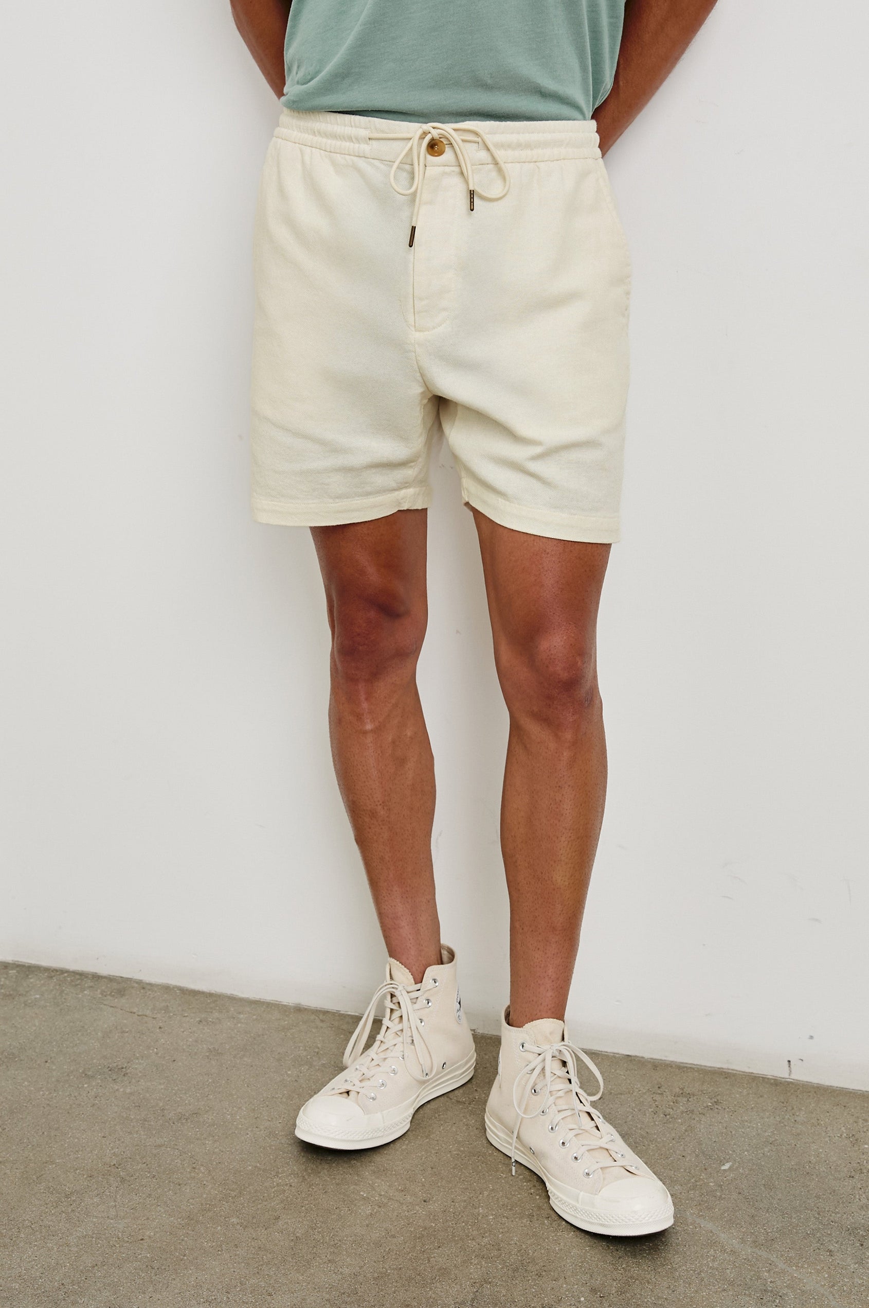 Archer medium length cotton short with adjustable drawstring and front button closure in Ecru - front view on model.
