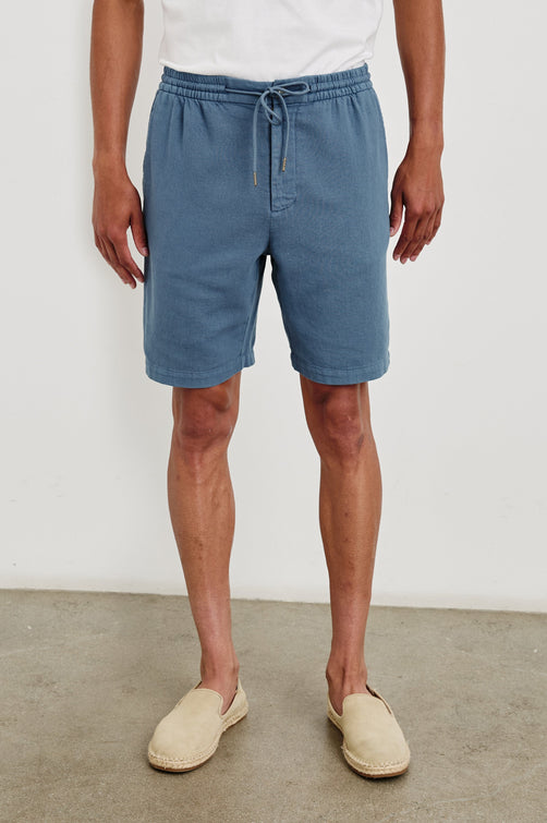 Archer long length cotton short with adjustable drawstring and front button closure in Washed Blue - front view on model