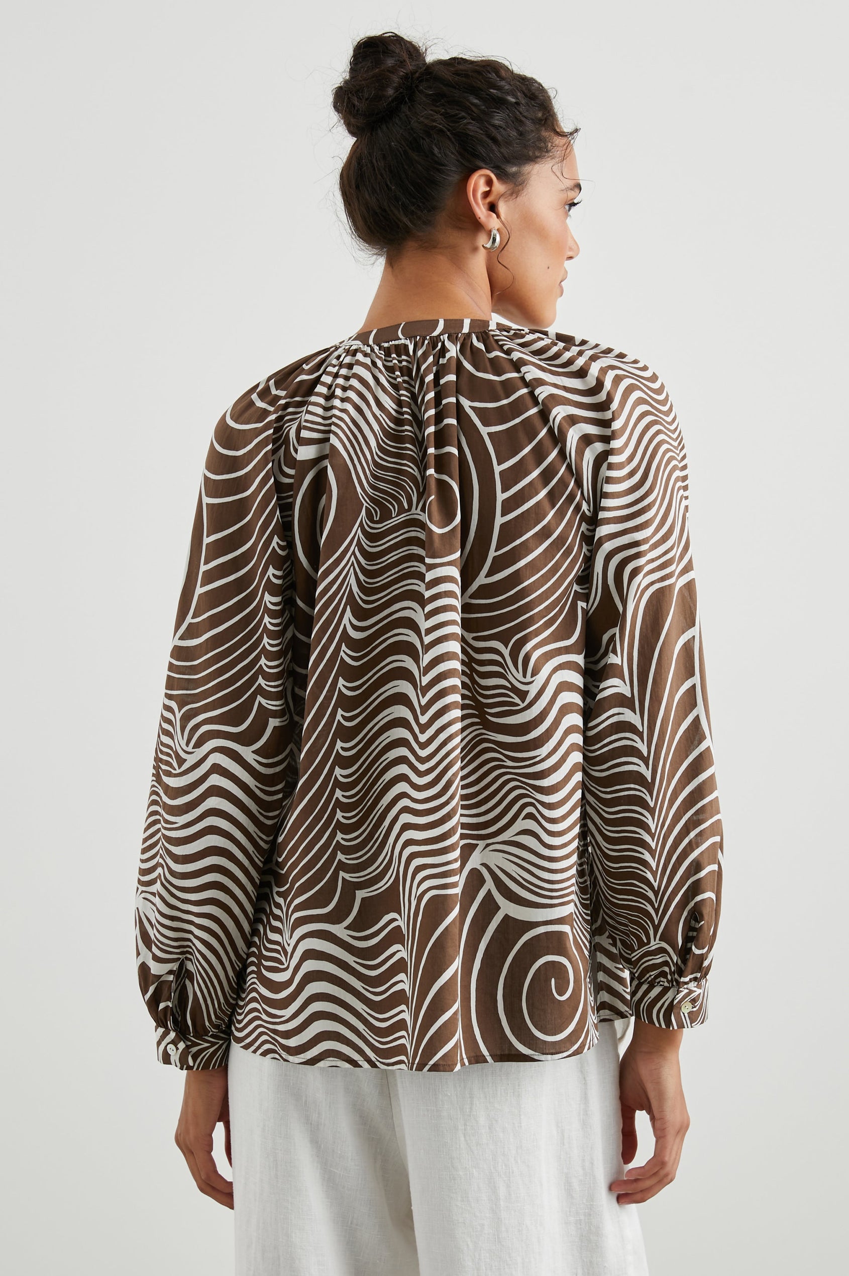 Brielle Long-Sleeve Top with a Deep V Neck with Ties and Pleats around the Neckline in Swirls Colorway, with white swirls on brown - Back View Featured on Model