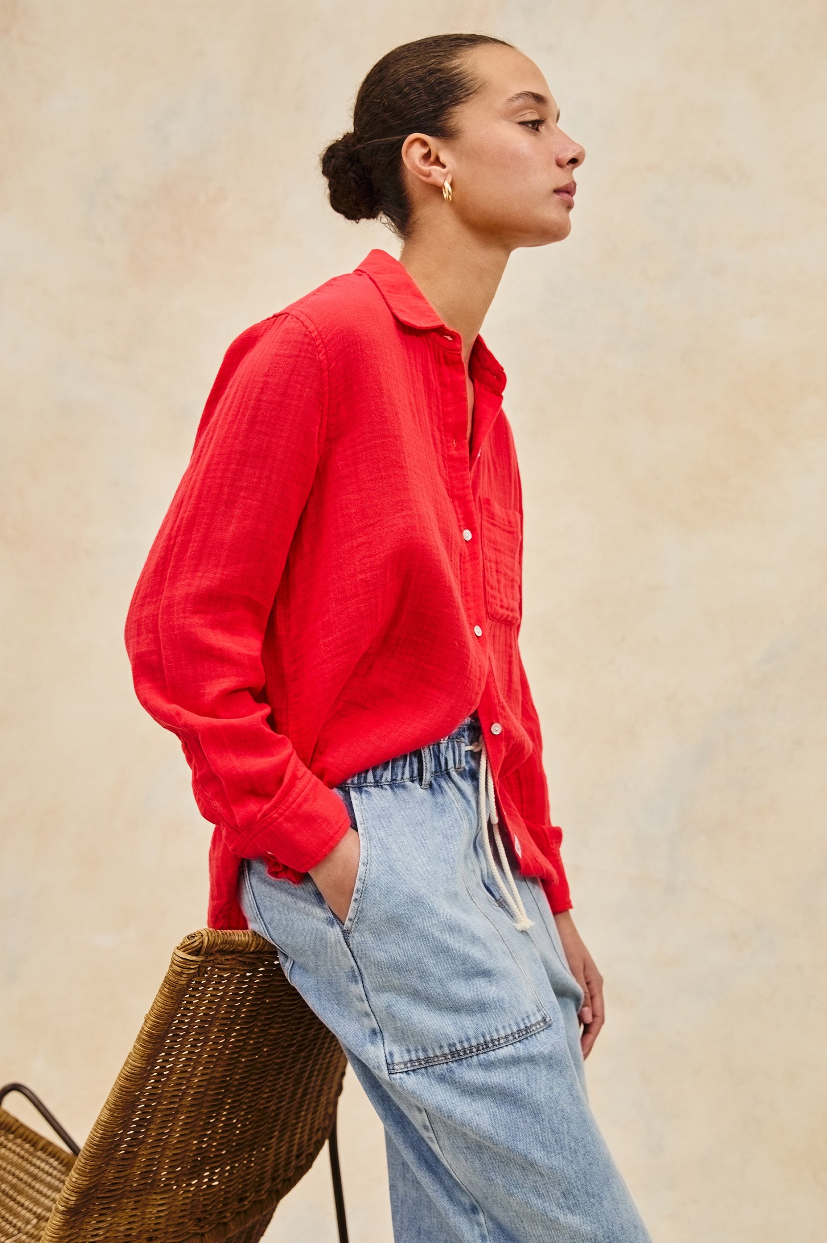 Ellis long sleeve loose fitting button up with single chest pocket in Cherry - on model leaning on chair, side view