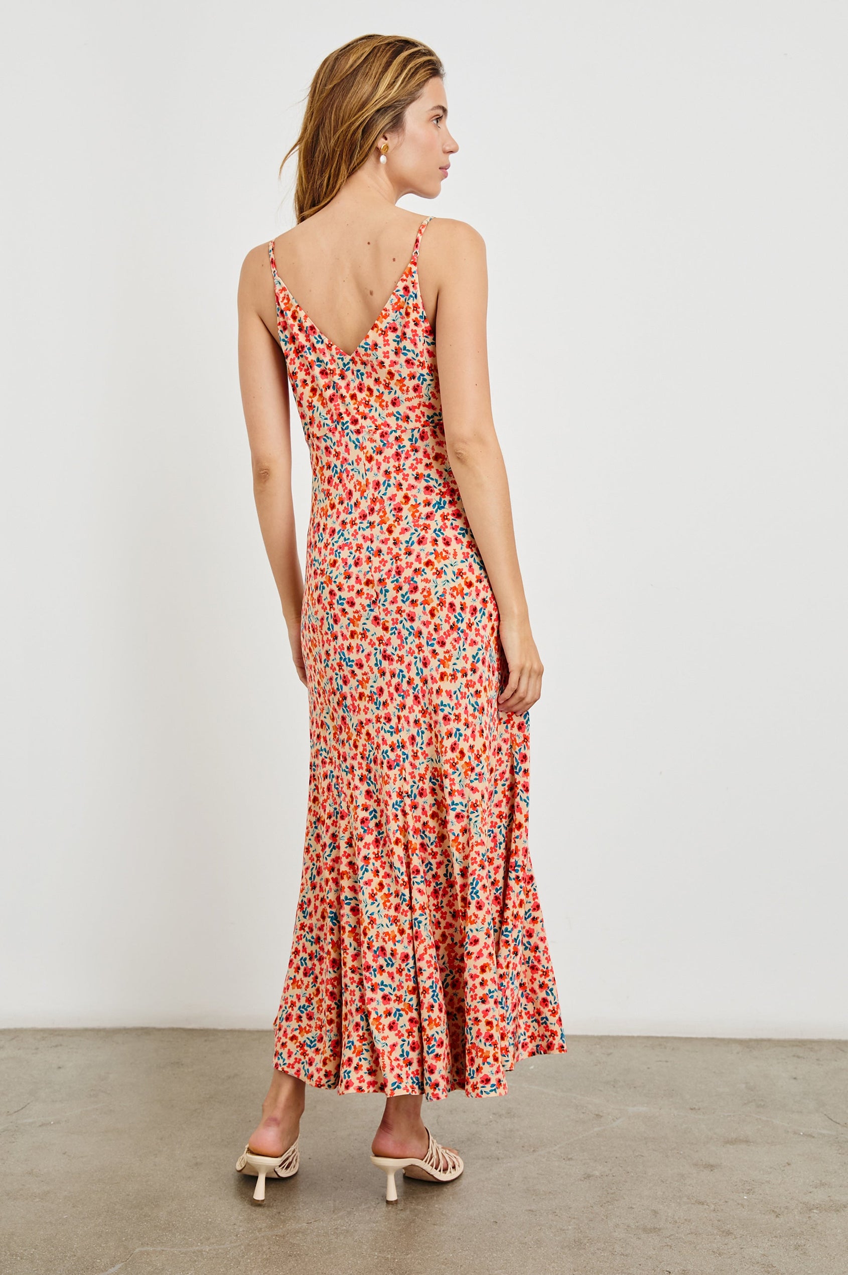 Florian Midi Dress with a V-Neckline, Spaghetti Straps, and Buttons down the front in Red Posy Colorway, Red, Blue and Orange on Tan - Back Full Body View Featured on model