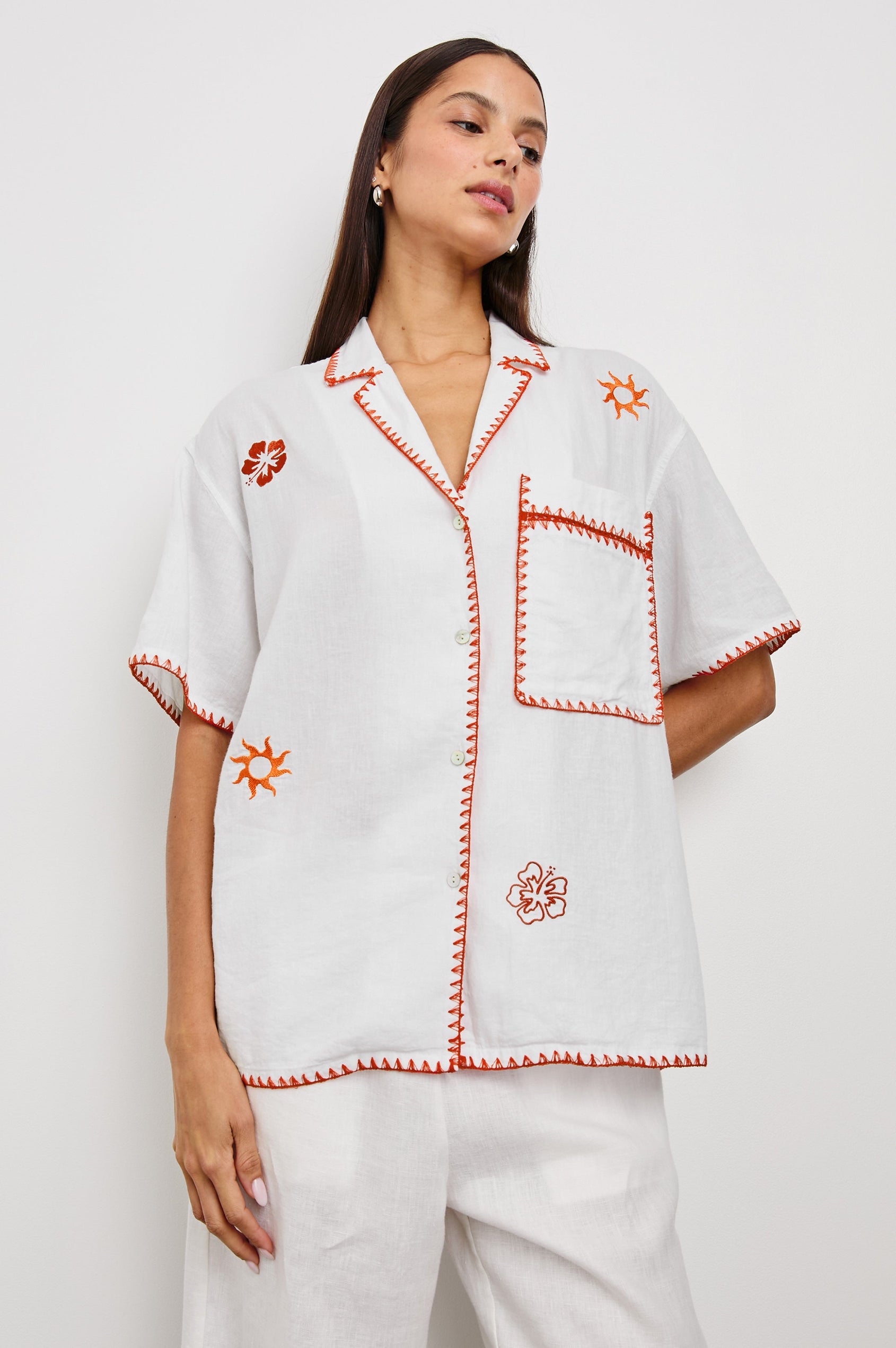 Island Short-Sleeve, Button-Down Shirt with Flat Collar, Large Chest Patch Pocket, Embroidered Decorative Trim and Embroidered Flowers and Sun in Red and Yellows in White Colorway - Front View Featured on Model