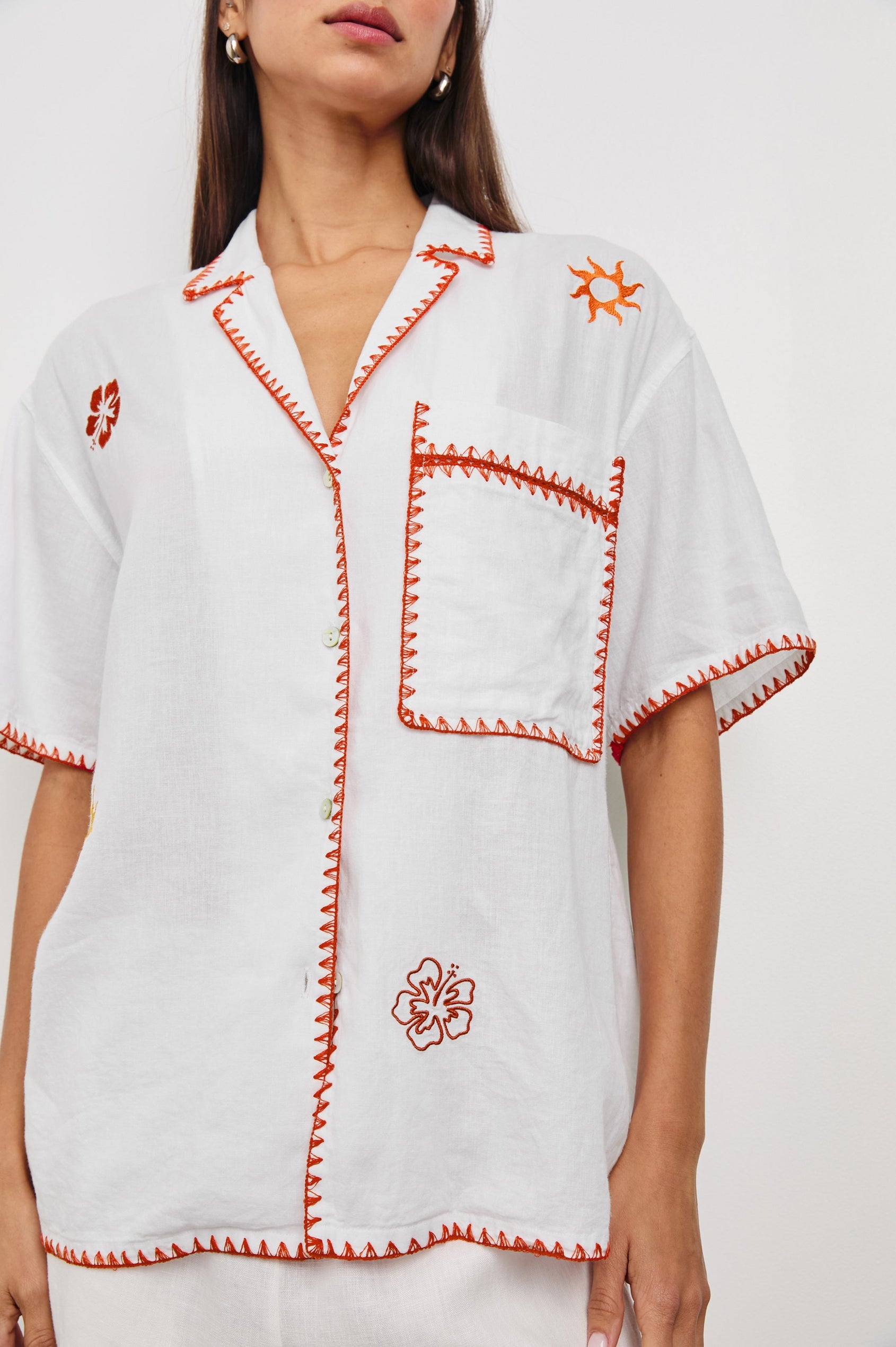 Island Short-Sleeve, Button-Down Shirt with Flat Collar, Large Chest Patch Pocket, Embroidered Decorative Trim and Embroidered Flowers and Sun in Red and Yellows in White Colorway - Front View Featured on Model