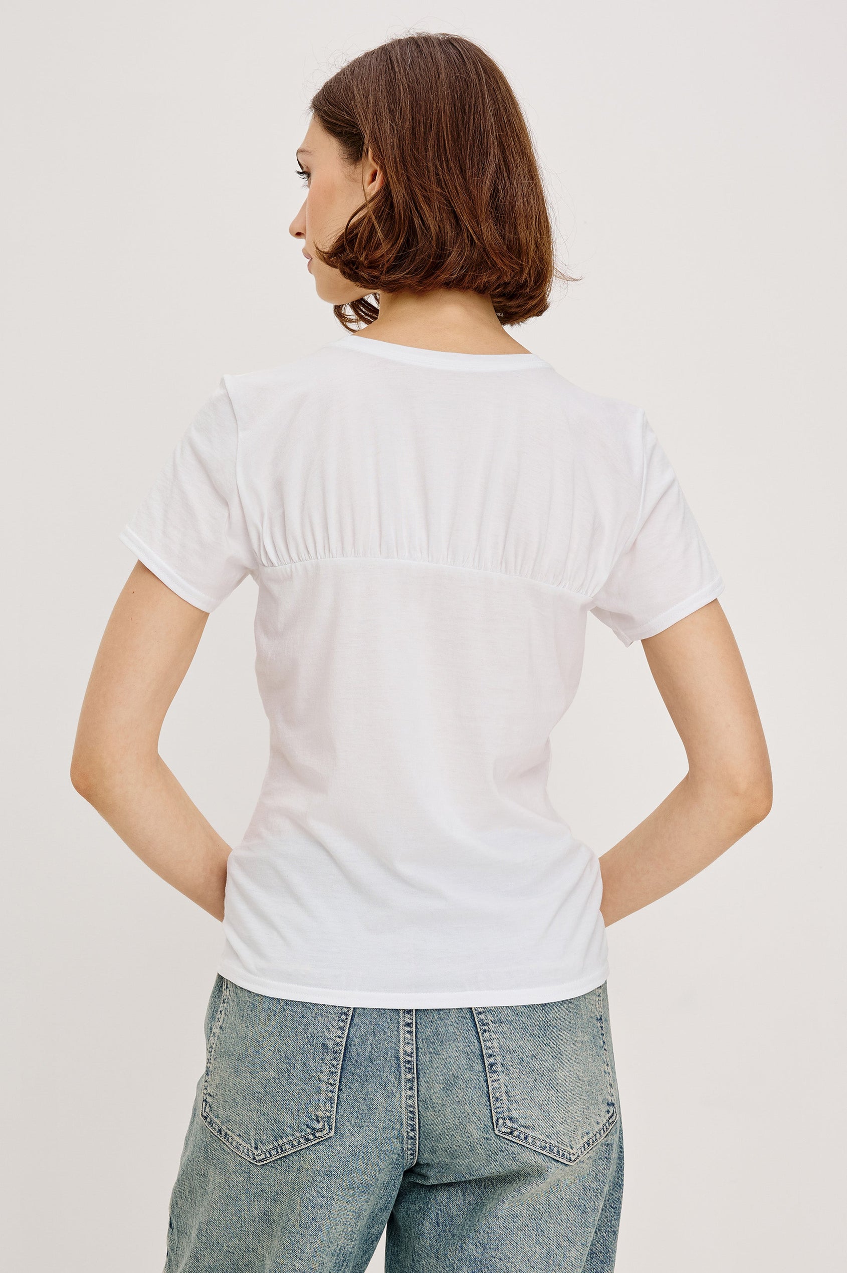 Janis short-sleeve cotton t-shirt with a sweetheart neckline and gathered, shirred detailing at the chest in White Colorway - back view featured on model with shirt tucked in and styled with a western belt.