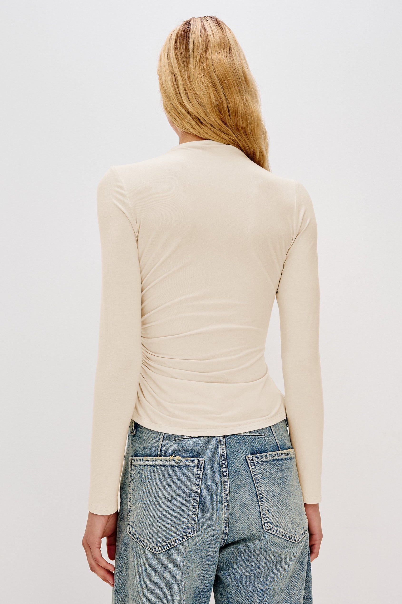 Joelle Long Sleeve Top with An Asymmetrical Mock Neck and Shirring on the Right Shoulder in Ivory Colorway - Back View Featured on Model