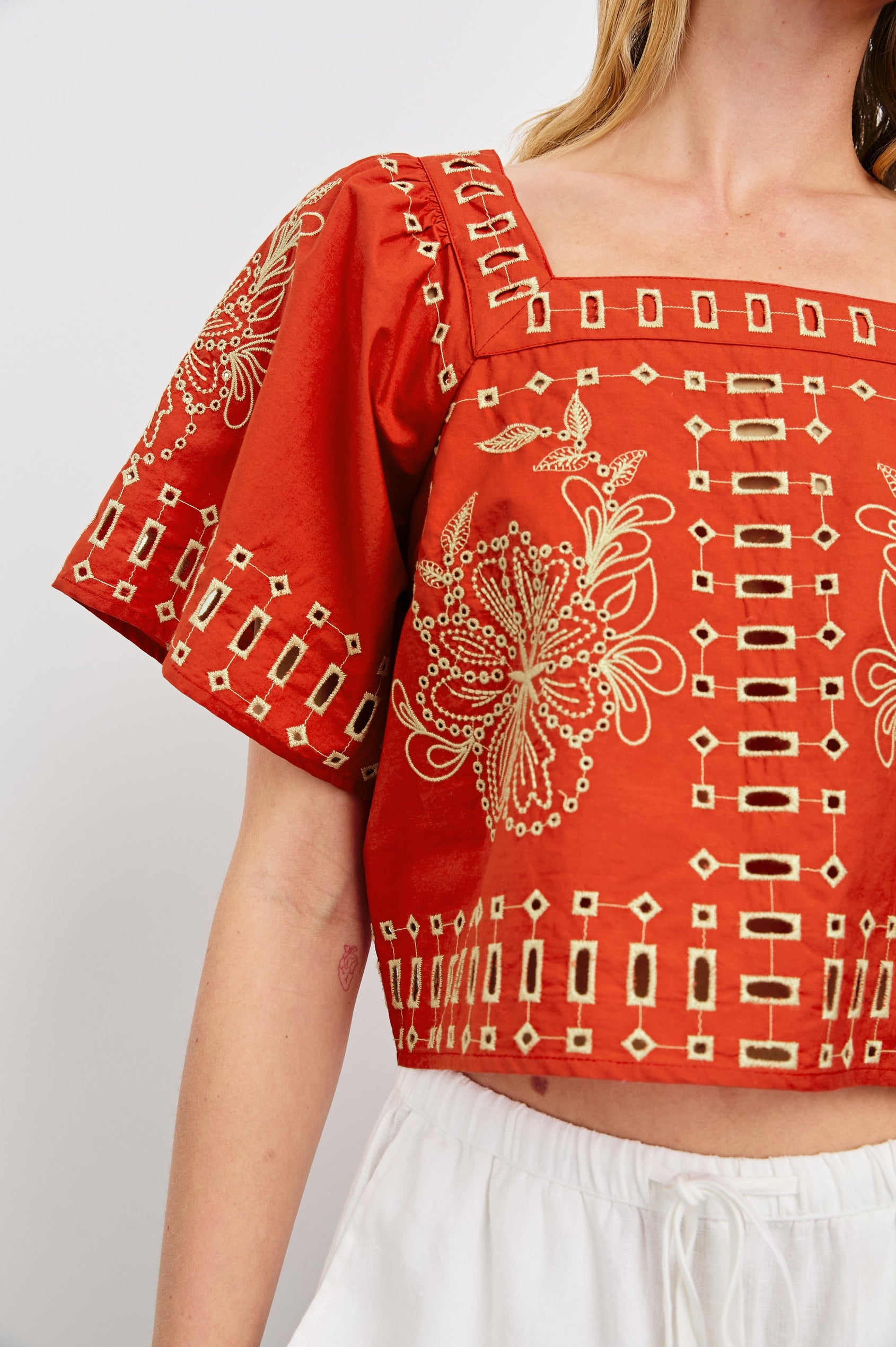 Laine airy cotton poplin top with wide short sleeves and a loose fit. Contrast eyelet embroidery in color Terracotta - close up of details on model
