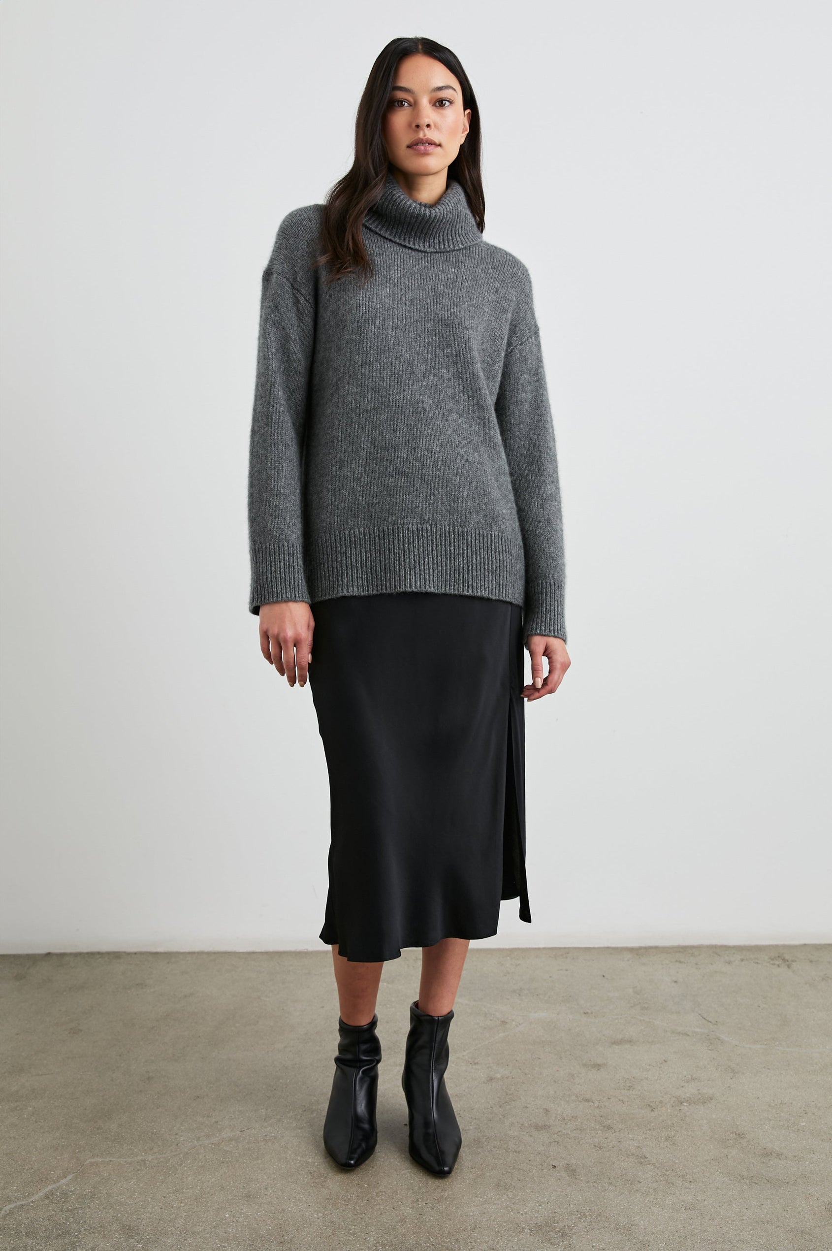 Maya Midi Skirt with Mid-Thigh Side Slit in Black Colorway - Front Full Body View Featured on Model