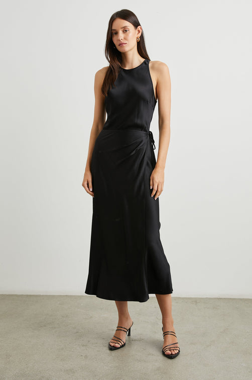Navi Sleeveless Midi Dress with a Halter Neckline with a Back Tie Keyhole, and a Wrap Skirt with a Side Tie Closure in Black Colorway - Front Full Body View Featured on Model