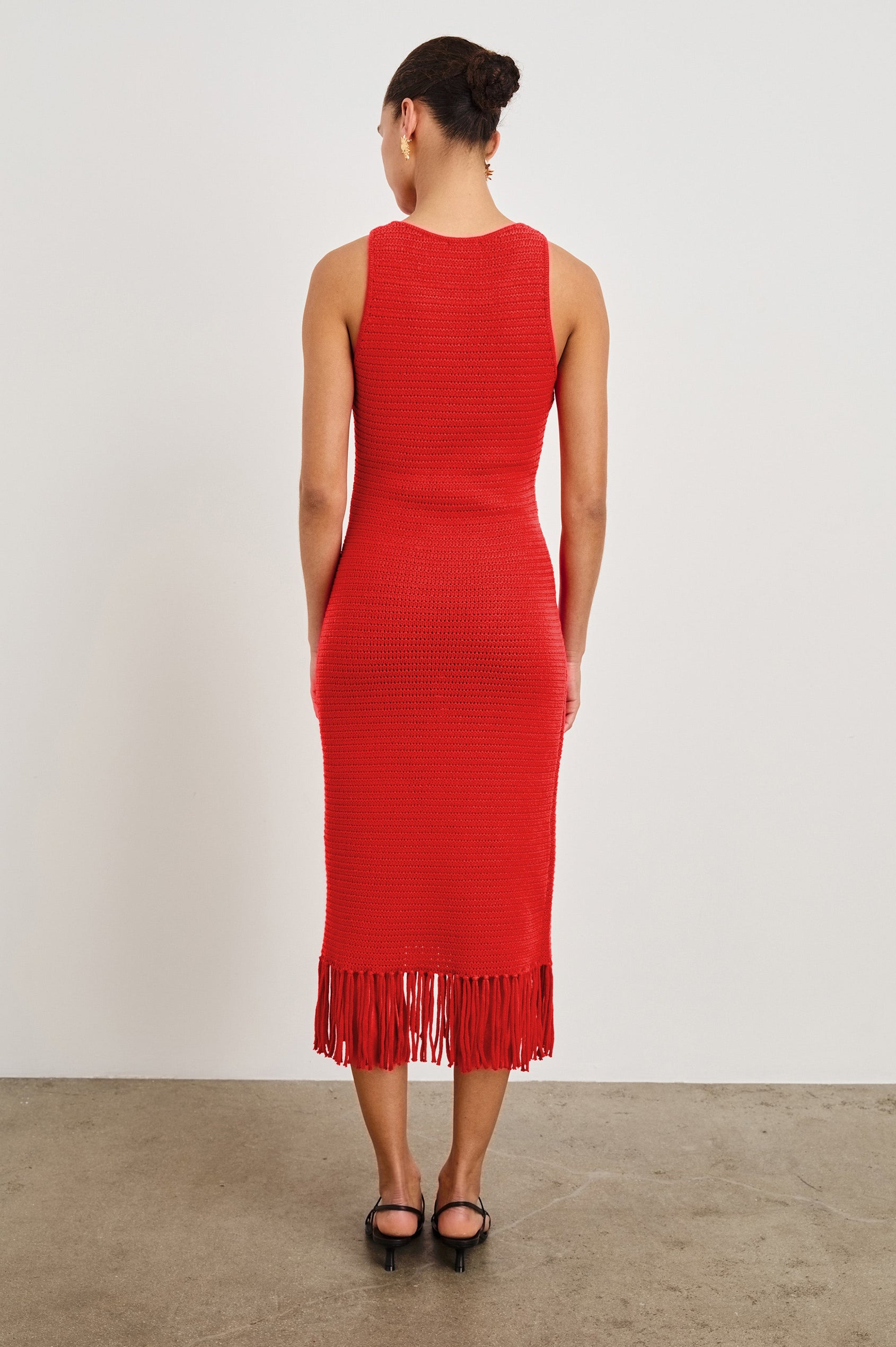 Back view of female model wearing our sleeveless, Nia Midi Dress in color Cherry, featuring crochet structure and fringe details at the hem.