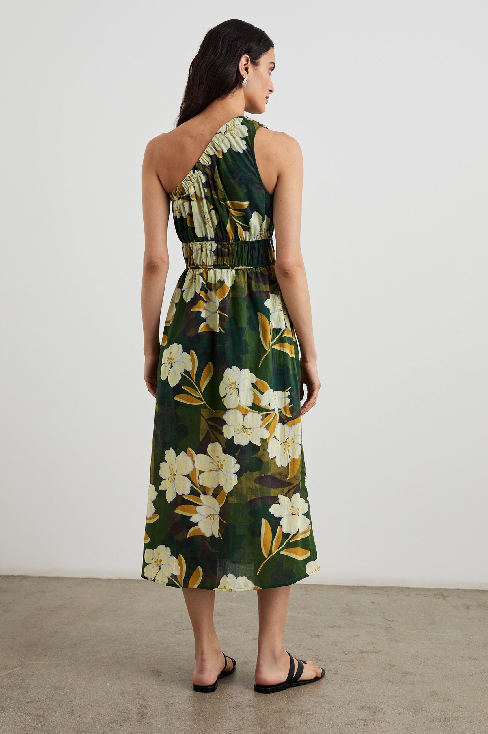 Selani Midi Dress With an Asymmetrical Neckline, Mid-Thigh Slide Slit and Cinched Waistband in Plumerias Colorway, with Ivory and Gold Plumerias on Dark Green - Back Full Body View Featured on Model
