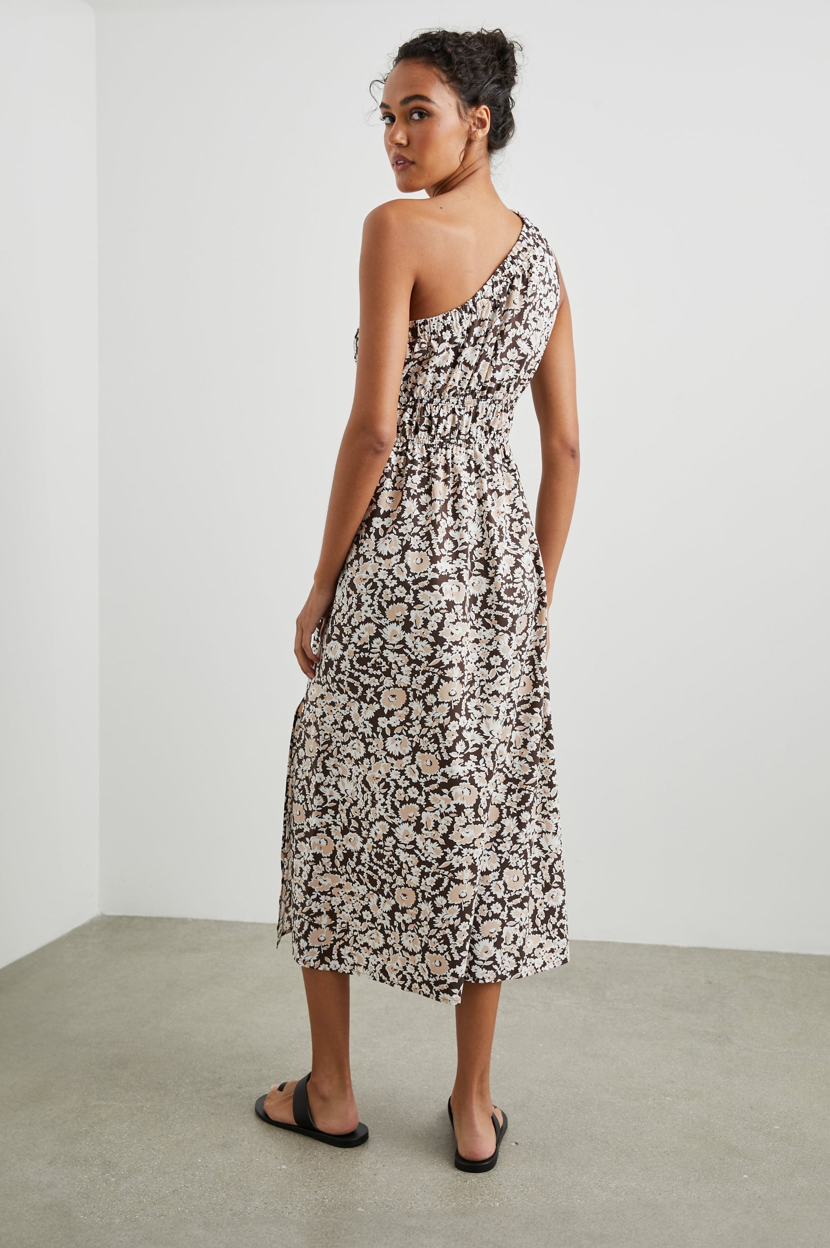 Selani Midi Dress With an Asymmetrical Neckline, Mid-Thigh Slide Slit and Cinched Waistband in Russet Floral Colorway, with white and tan flowers on russet - Back Full Body View Featured on Model