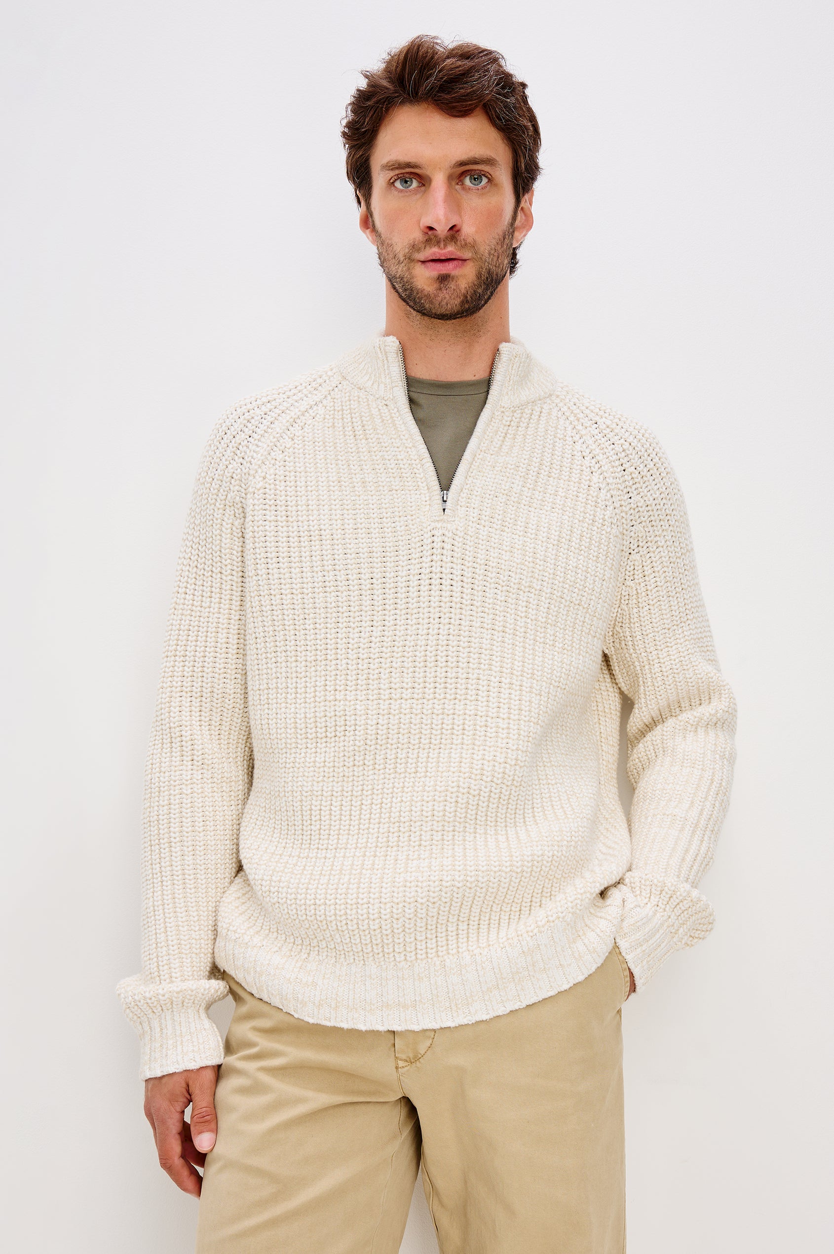 Stratton is a quarter-zip long sleeved sweater knitted from chunky cotton blend knit in Snowdrift Marl colorway. Front view featured on model.