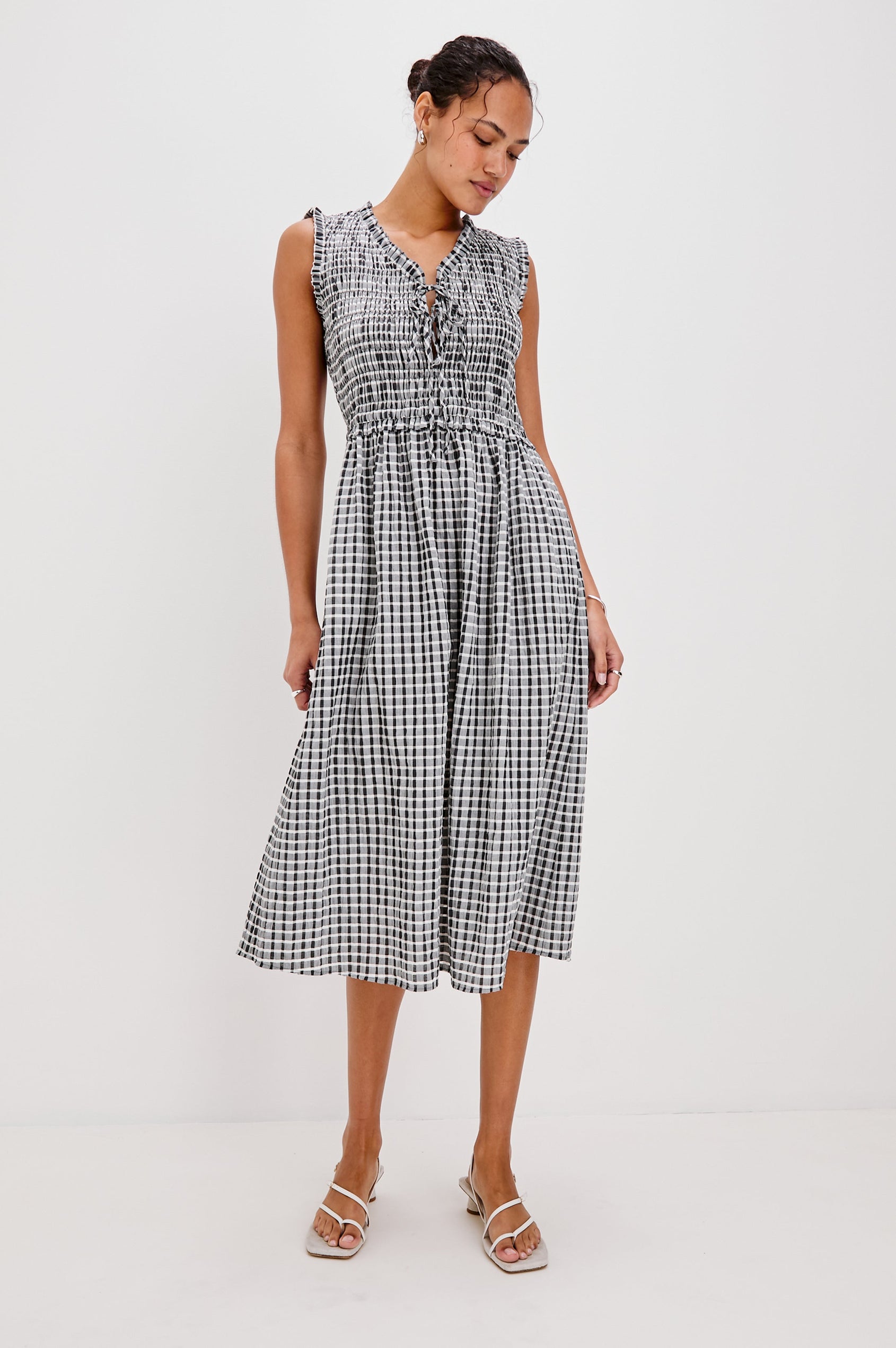Adine Below-Knee Tank Dress with a Ruffle Edge V-Neck and Armhole, Tie Front, Gathered Bodice and A-Line Skirt in Ash Seersucker Colorway. Full Body Front View Shown on Model.