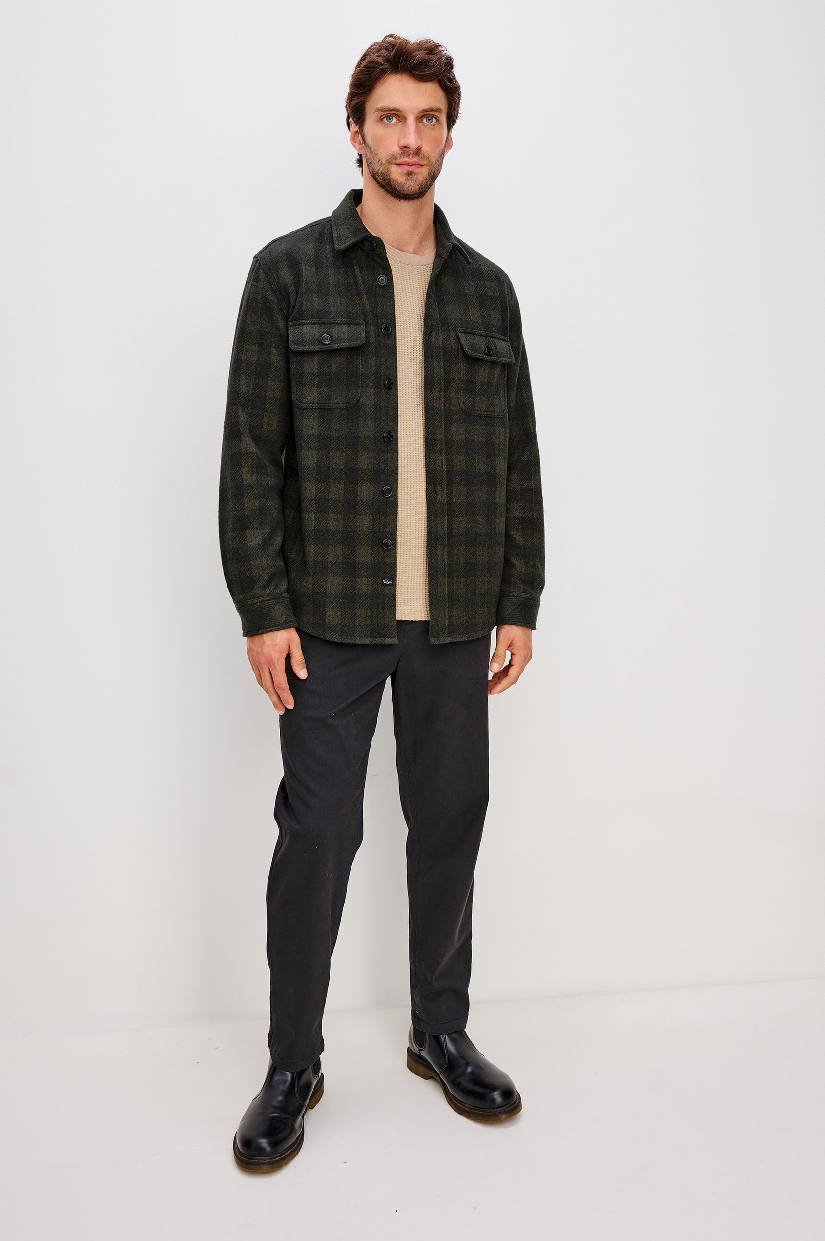 Alder Long-Sleeve Button up with Two Buttoned Chest Flap Pockets in Onyx Surplus Colorway, a Green and Black plaid. Front Unbuttoned Full Body View Featured on Model