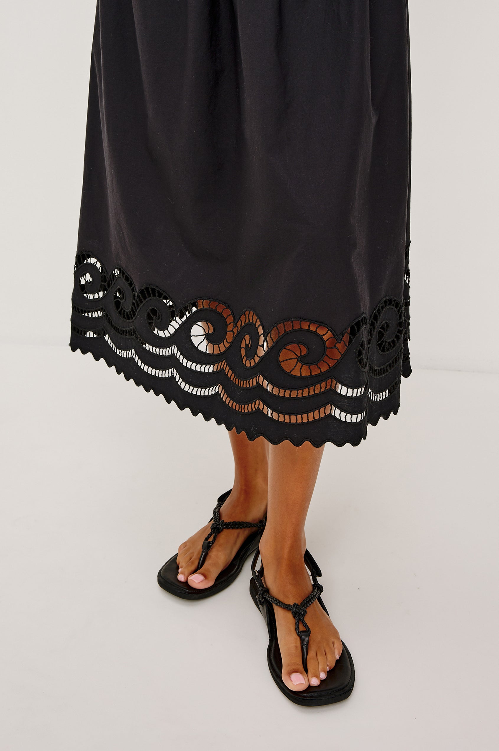 Anadia Maxi Dress in Poplin With Soutached Swirl Shoulder Straps, Ruched Bust, Smocked Empire Waist, and Scalloped Ladder Embroidered Hem in Black Colorway - Lower Body Close Up View Featured on Model