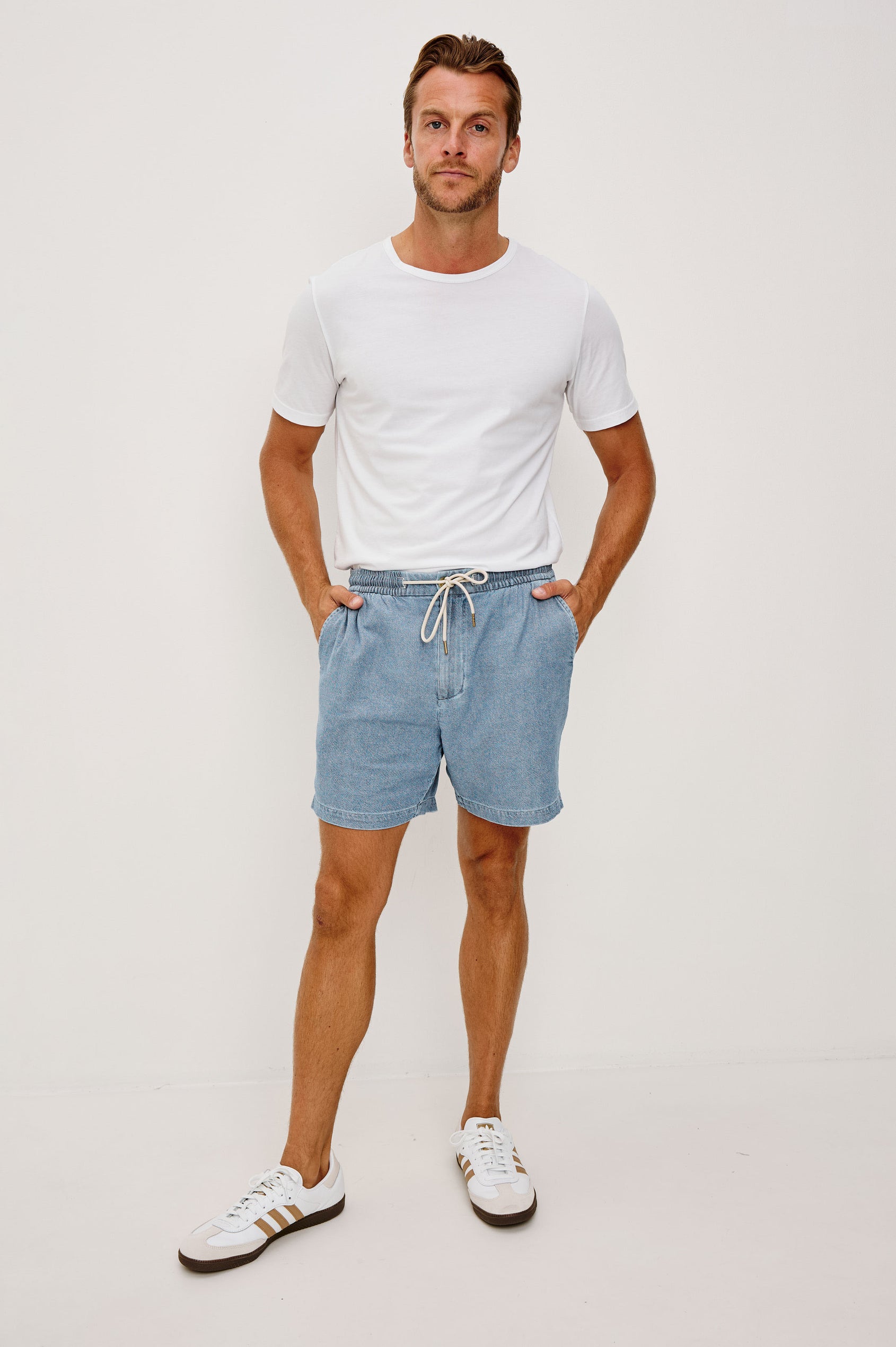 Archer Short in Unlined Cotton Linen With Relaxed Fit, Adjustable Waist Drawstring Ties, Side Pockts, and 6-Inch Inseam in Medium Wash Indigo Colorway - Full body front View Featured on Model