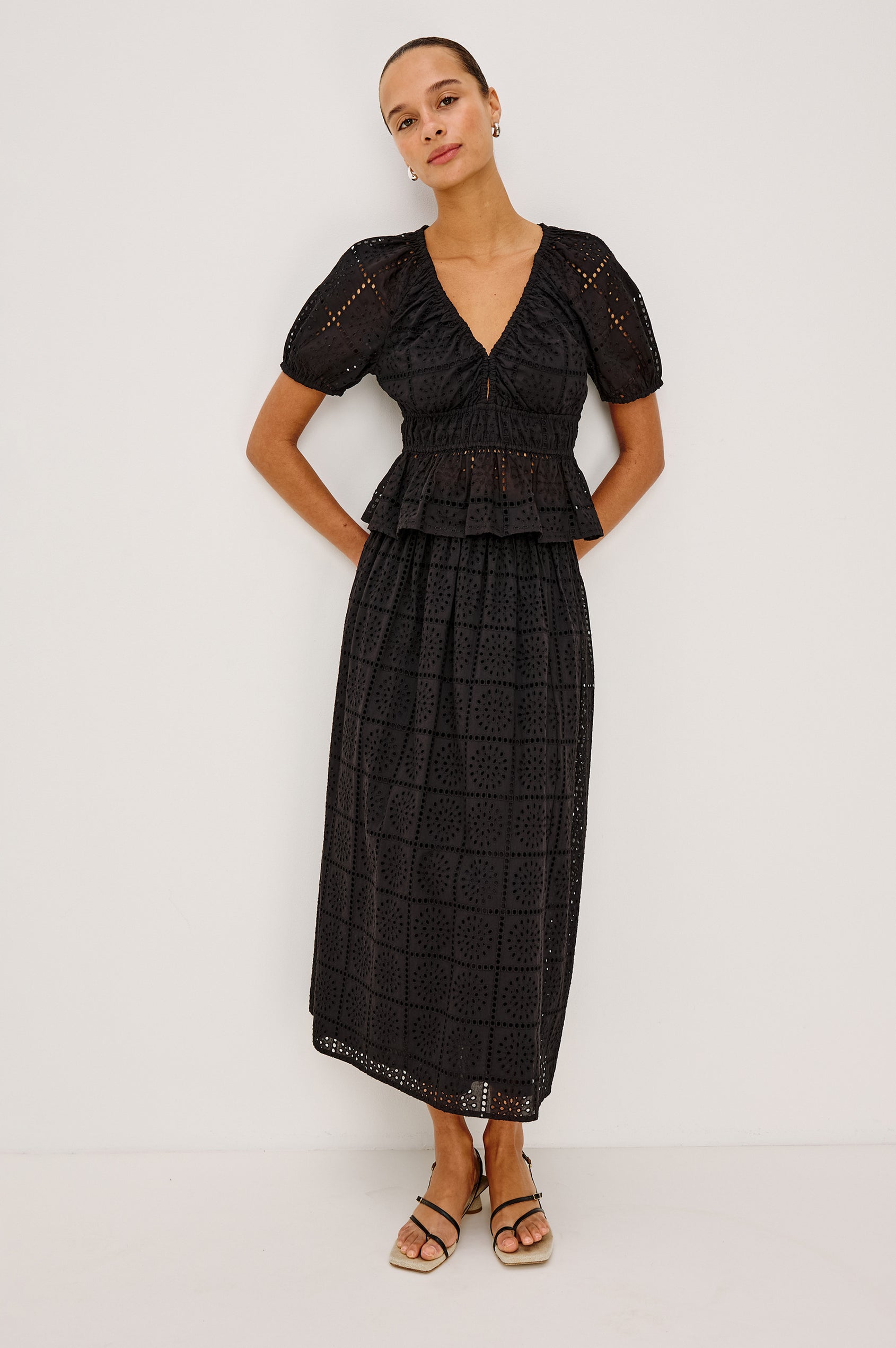Argenta Top in Cotton Voile With Embroidered Pattern, Short Puff Sleeves, Hook-and-Eye Closure, Elastic V-Neckline and Waist, and Peplum Hem in Black Grid Embroidery Colorway - Full Body Front View Featured on Model