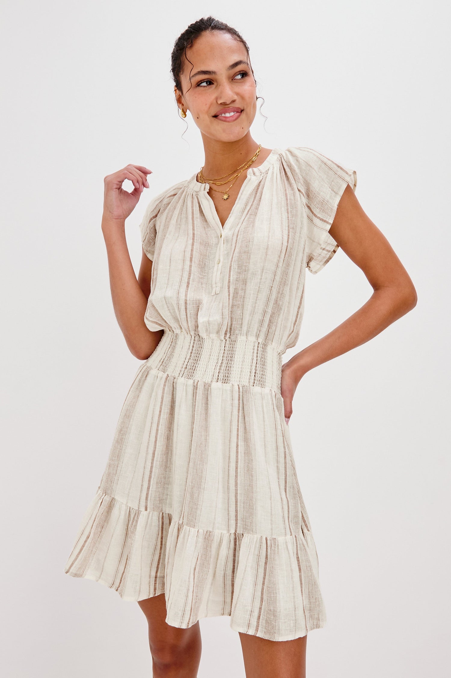 Augustine Mini Dress with Flutter Sleeves, V-Neck Button Front, Elastic Gathered Waist and a Tiered Flounce Hem in Jalisco Stripe Colorway. Front View Shown on Model.