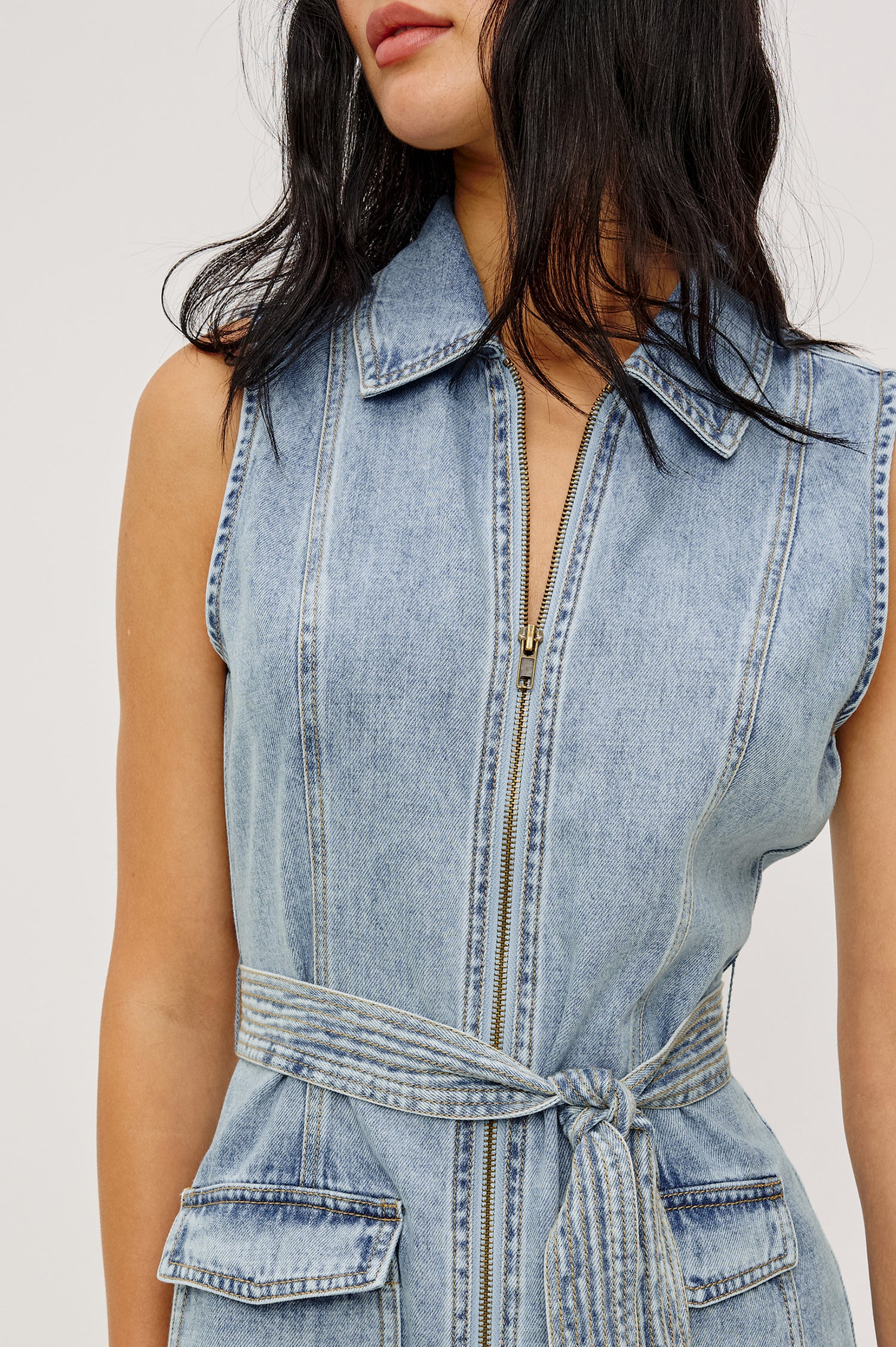 Aurora Sleeveless Mini Dress in TENCELâ„¢Denim With Collar Front Exposed Zipper Adjustable Belted Ties Side Flap Pockets in Faded Indigo Colorway - Upper Body Close Up Front View Featured on Model
