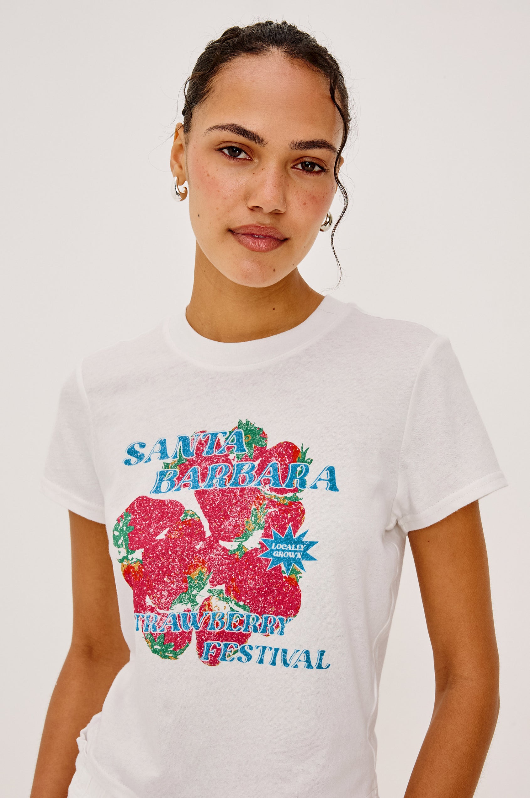 Baby Tee in Cotton With Crew Neckline, Short Sleeves, Boxy, Cropped FIt, and Graphic Print at Front in Santa Barbara Strawberry Festival Colorway - Upper Body Front Close Up View Featured on Model