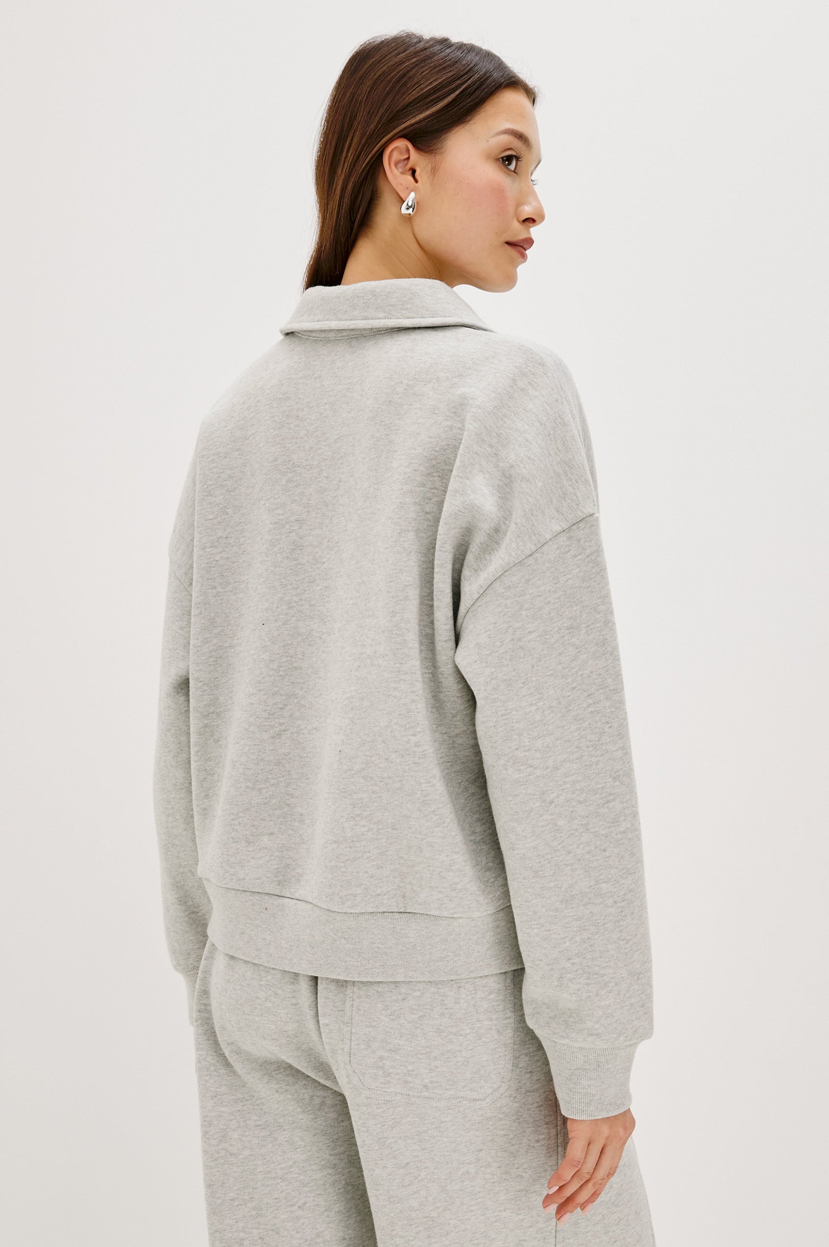 Cotton polo-style sweatshirt made from French terry fabric. The design features a button-front half placket, drop shoulders, and binding at the hem and cuffs for a relaxed, comfortable fit in Heather Grey Colorway - Back view featured on model 