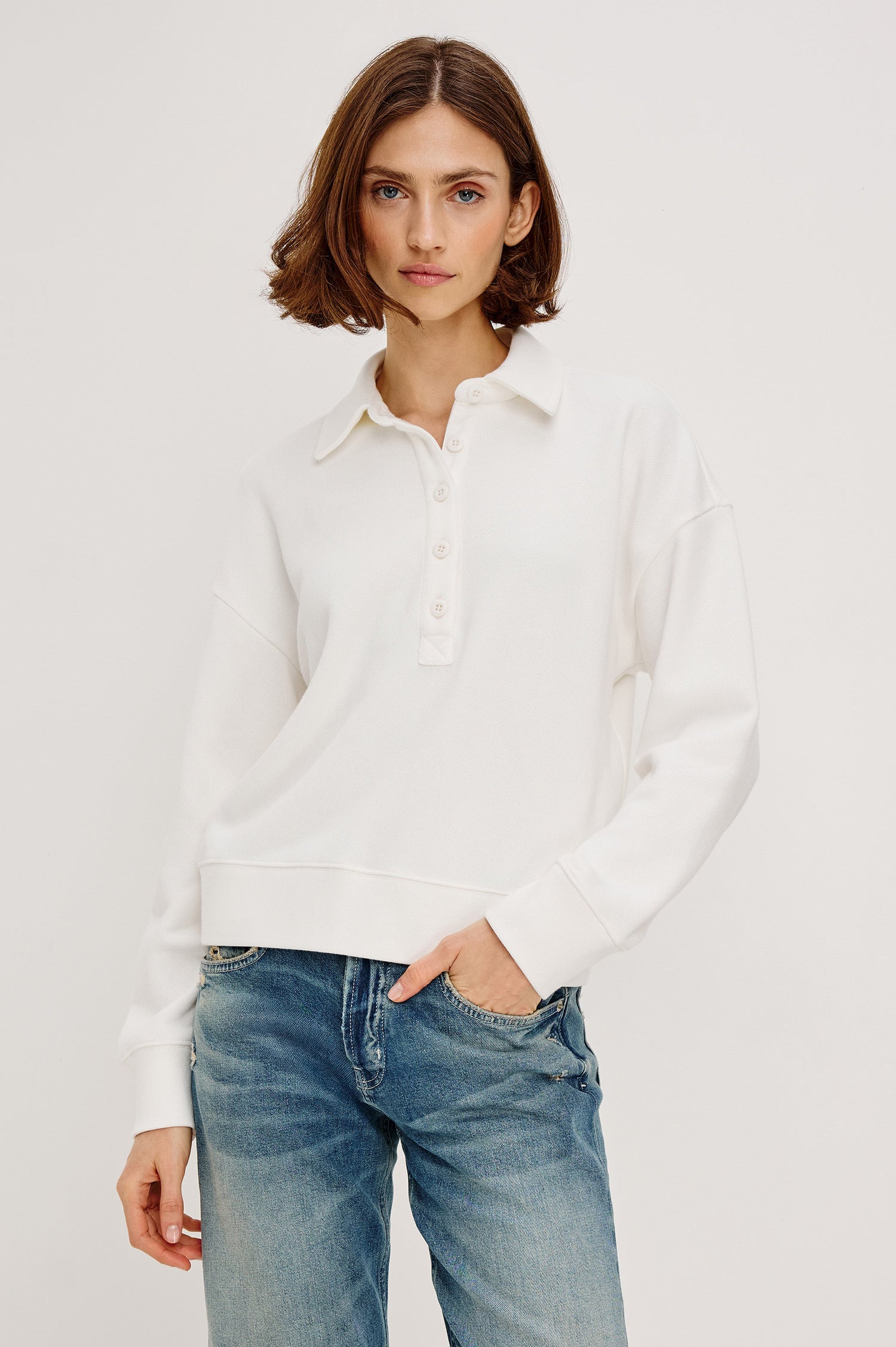 Cotton polo-style sweatshirt made from French terry fabric. The design features a button-front half placket, drop shoulders, and binding at the hem and cuffs for a relaxed, comfortable fit in Ivory Colorway - Front view featured on model