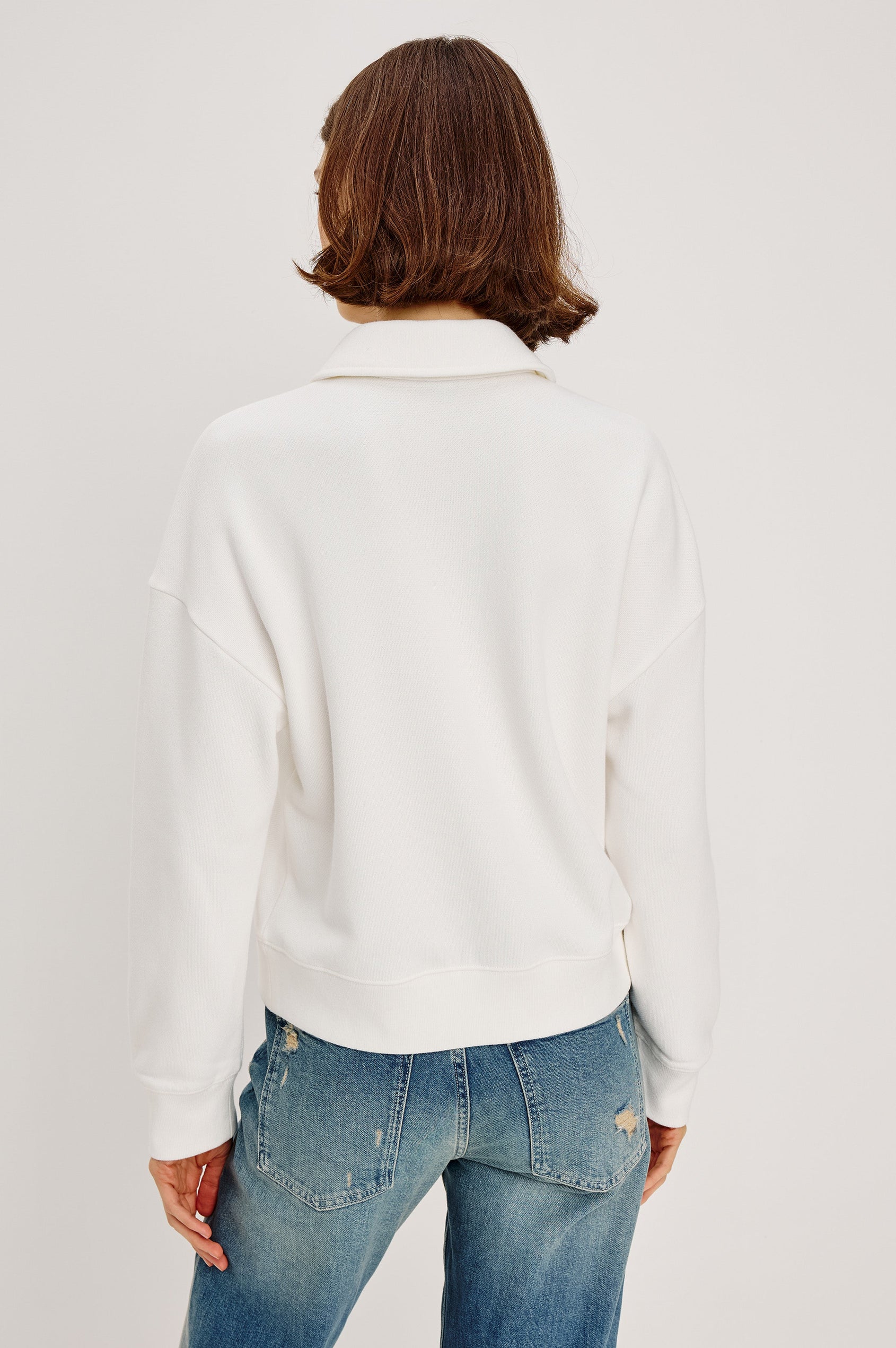 Cotton polo-style sweatshirt made from French terry fabric. The design features a button-front half placket, drop shoulders, and binding at the hem and cuffs for a relaxed, comfortable fit in Ivory Colorway - Back view featured on model