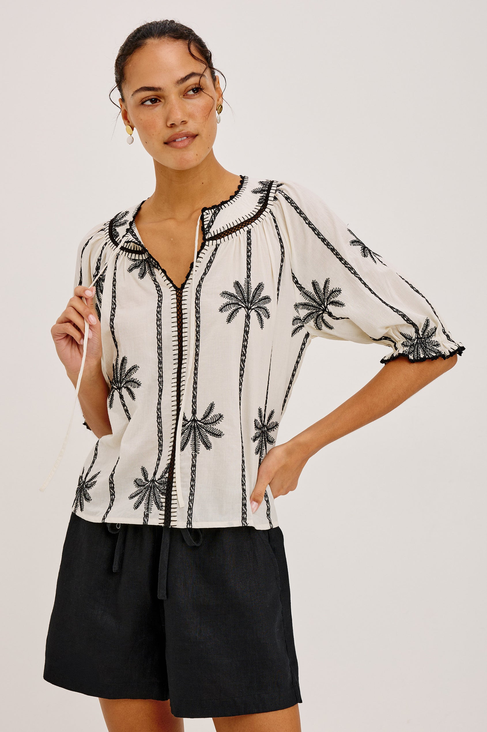Belina Peasant Top in Cotton Voile With Gathered V-Neckline With Self Ties, Loose Fit, and Elbow-Length Puff Sleeves With Elastic Cuffs in Embroidered Palms Colorway - Upper Body Front View Featured on Model