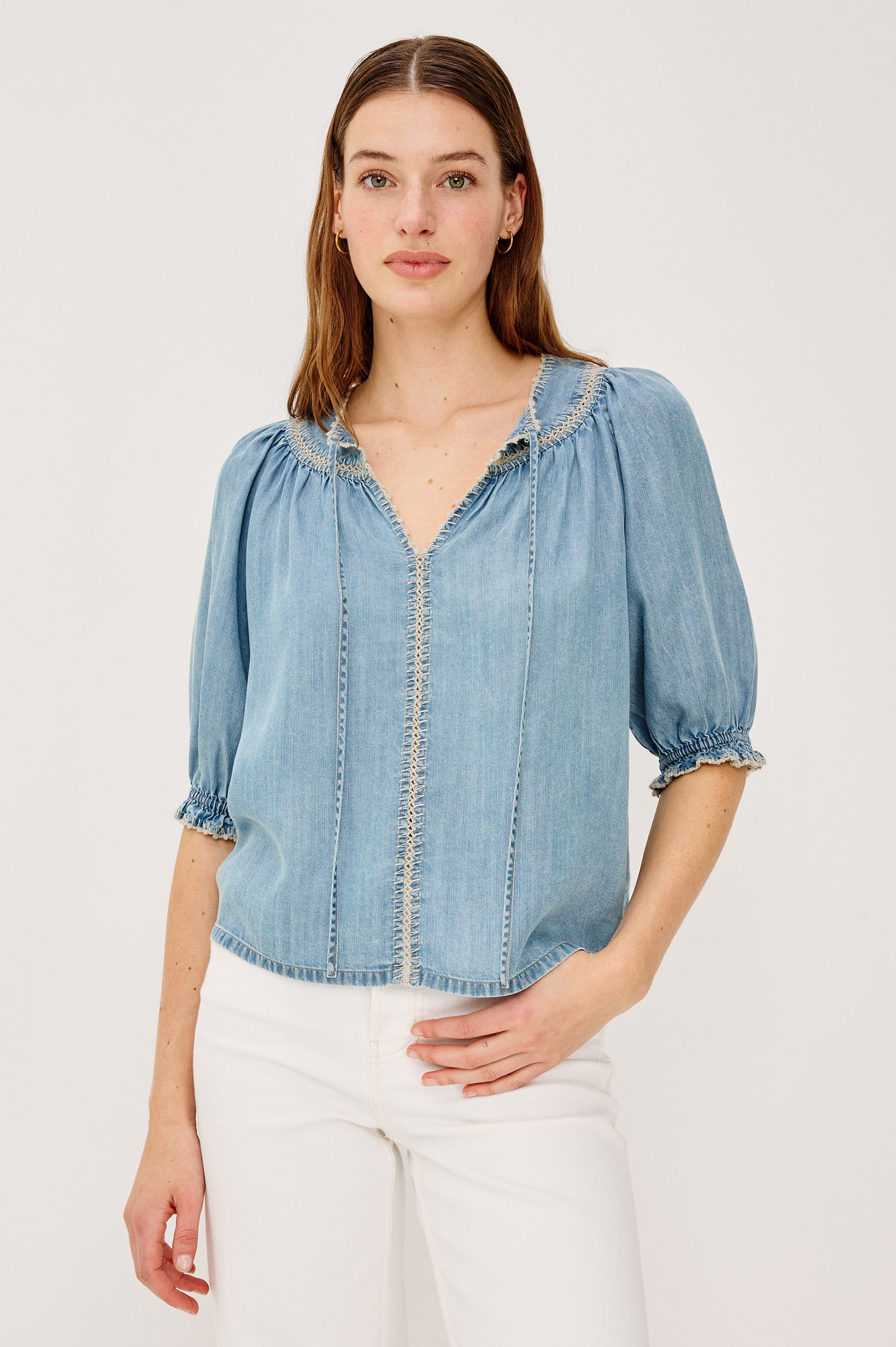 Belina Peasant Top in TENCEL™ Denim With Gathered V-Neckline With Self Ties Blanket Stitch Embroidered Trim Loose Fit and Elbow-Length Puff Sleeves With Elastic Cuffs - Upper Body Front View Featured on Model