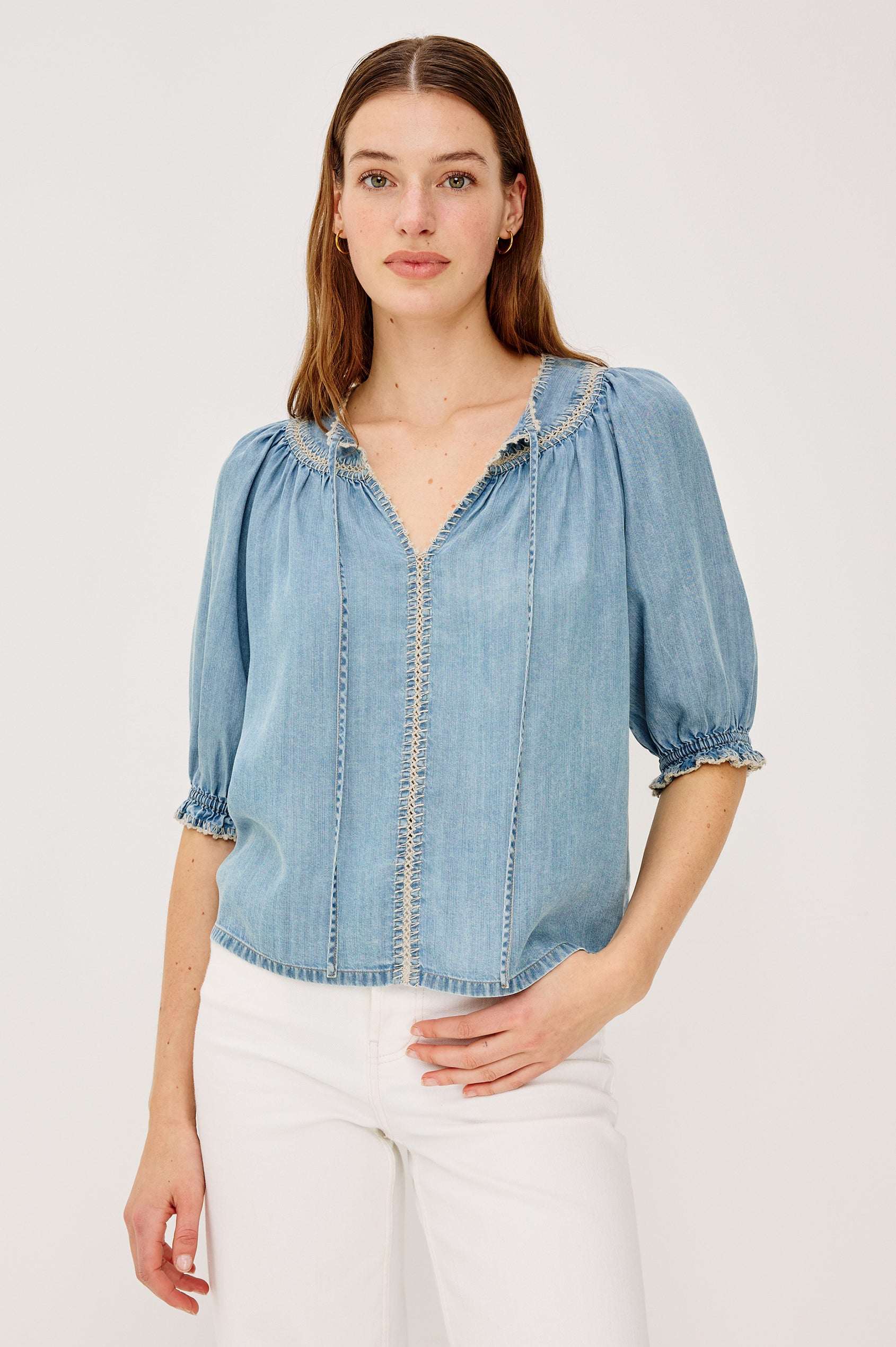 Belina Peasant Top in TENCELâ„¢ Denim With Gathered V-Neckline With Self Ties Blanket Stitch Embroidered Trim Loose Fit and Elbow-Length Puff Sleeves With Elastic Cuffs - Upper Body Front View Featured on Model