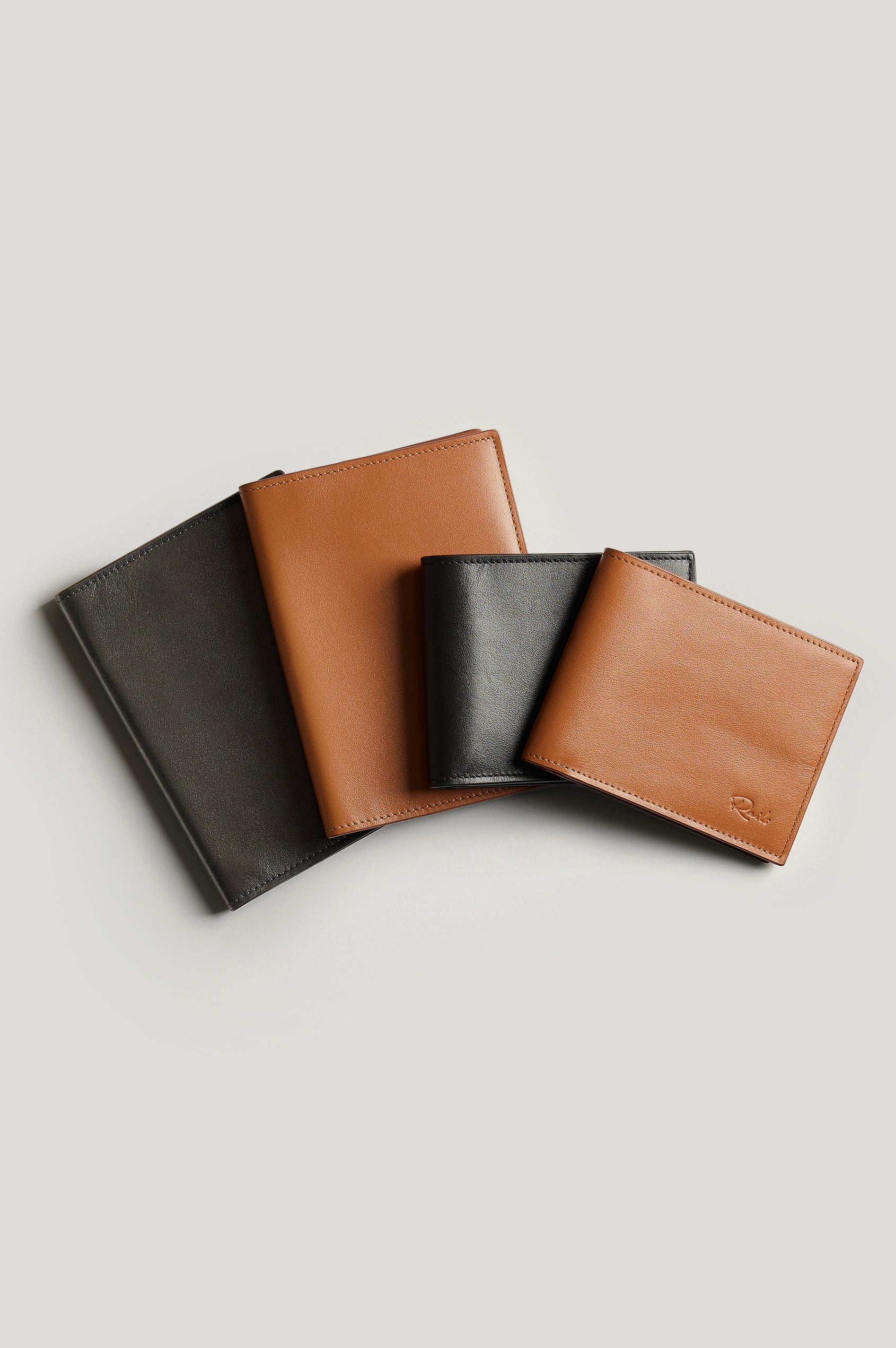 Leather wallet in cognac color, folded. Front folded view next to passports featured.