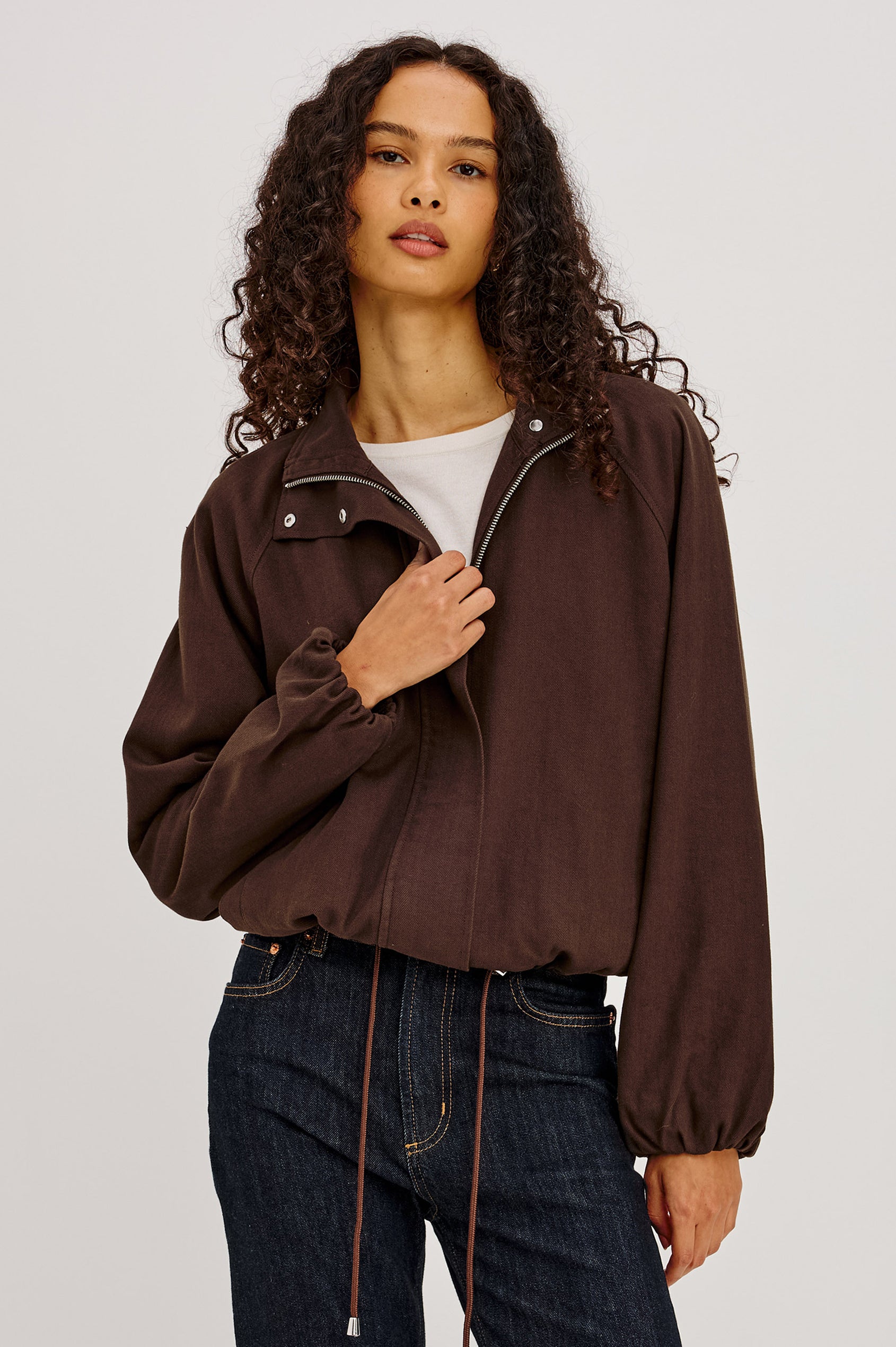 Blake Jacket in TENCEL™ Denim With Relaxed Fit, High Funnel Neck, Double Button Closures, Drop Shoulder Sleeves With Elastic Cuffs, and Cropped Drawstring Hem in Espresso Colorway - Upper Body Front View Featured on Model