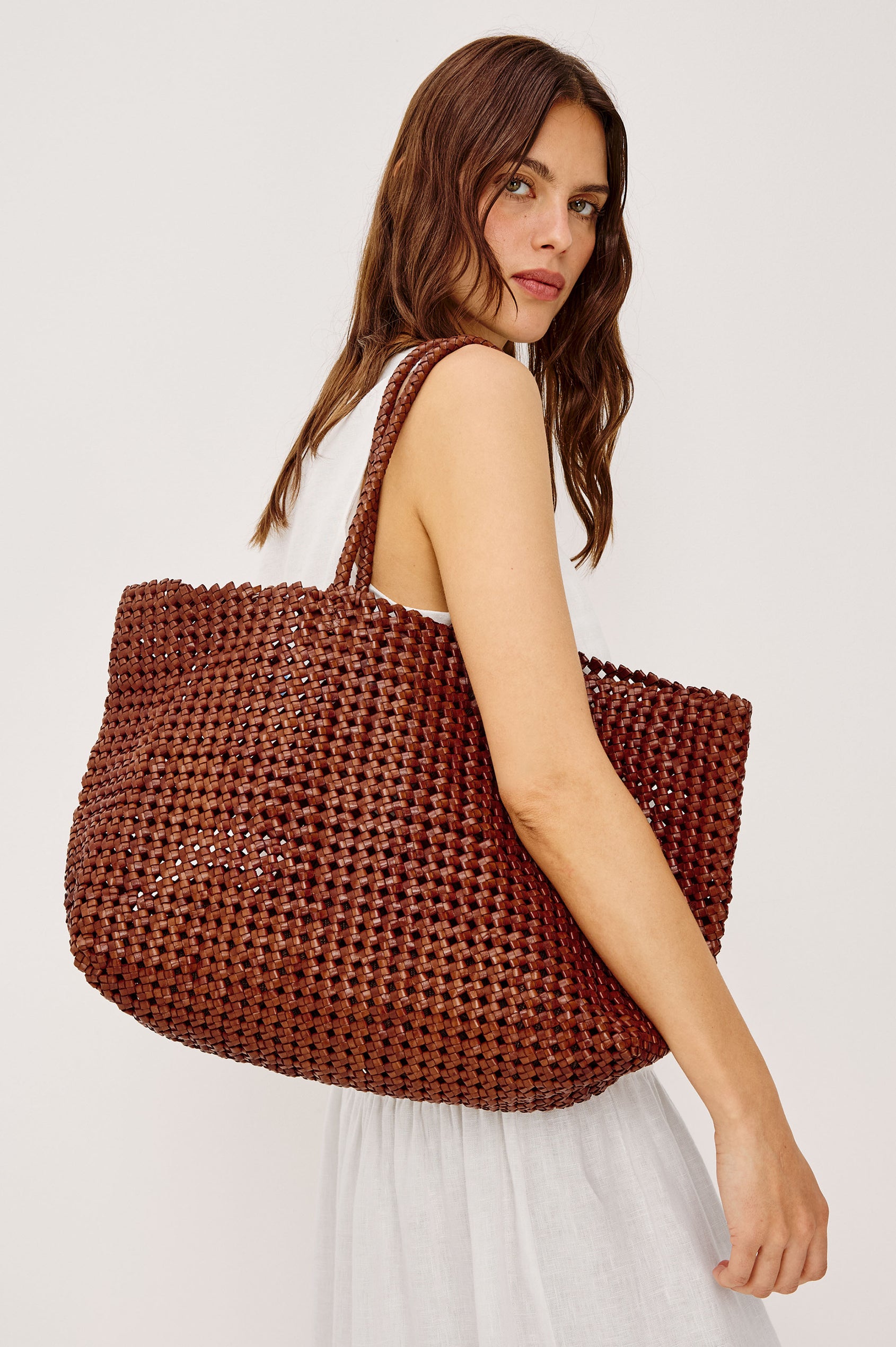 Brava Tote in Woven Leather With Top Handles and Spacious Interior in Cognac Colorway - Side View Featured on Model