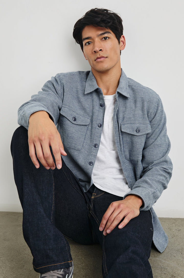 Burr Collared Shirt Jacket with Button Closure, Two Chest Button Flap Pockets and Textured Fabric in Denim White Colorway - Front Unbuttoned Full Body View Featured on Seated Model