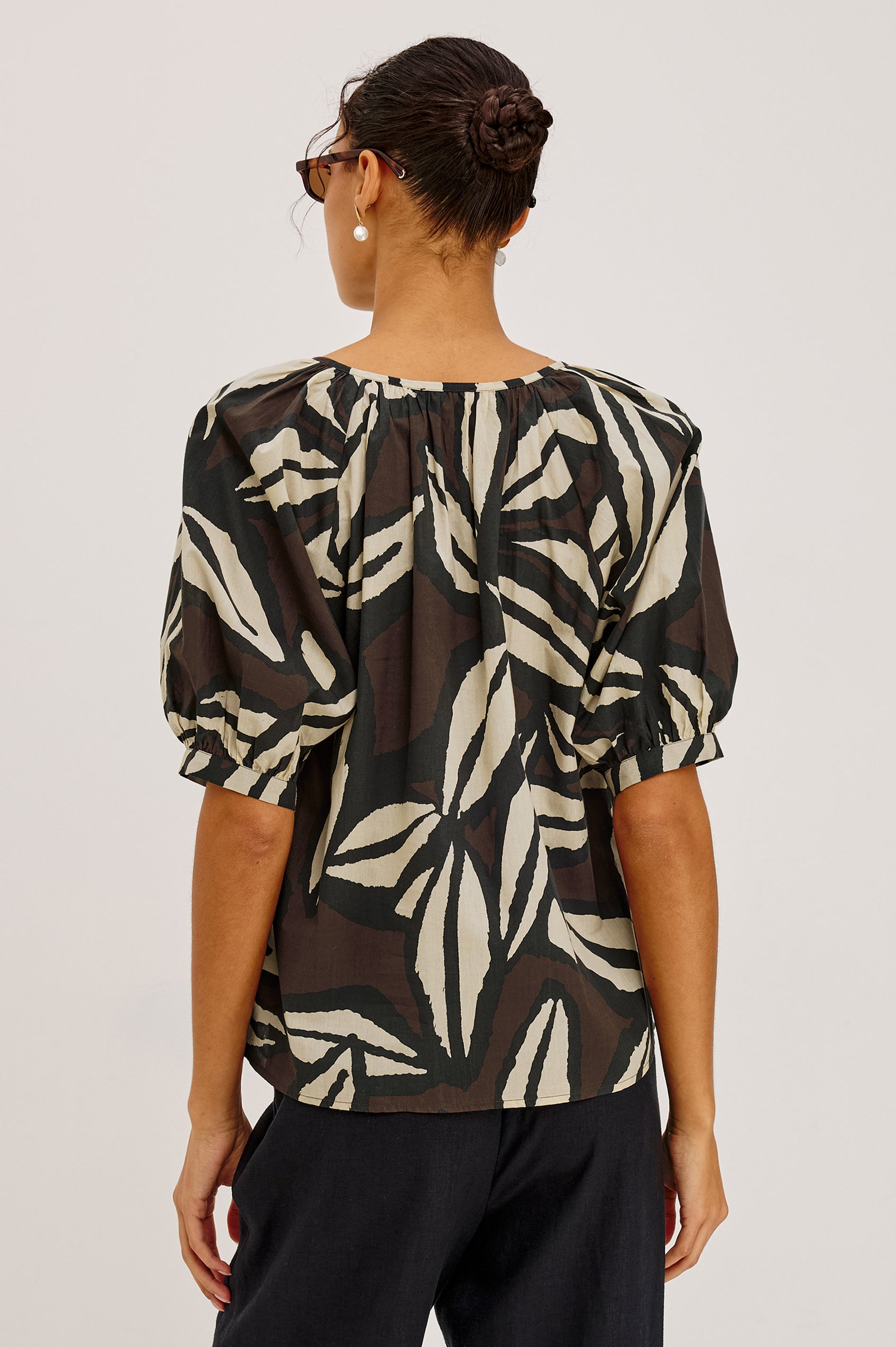 Catalene Peasant Blouse in Cotton Voile With Self-Tie V-Neckline, Loose Fit, and Short Puff Sleeves in Cocoa Floral Colorway - Upper Body Back View Featured on Model
