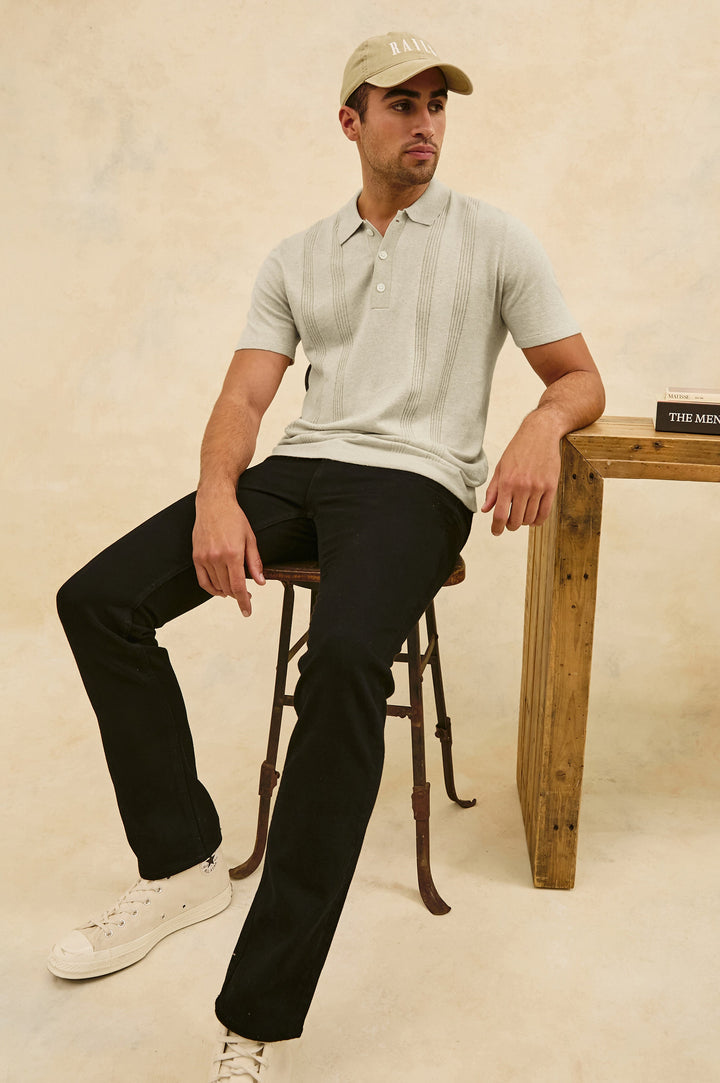 Cillian short sleeve cotton silk blend polo with three button placket and retro  front stripe details in Silversand - stylized view on model, sitting in chair with arm on desk