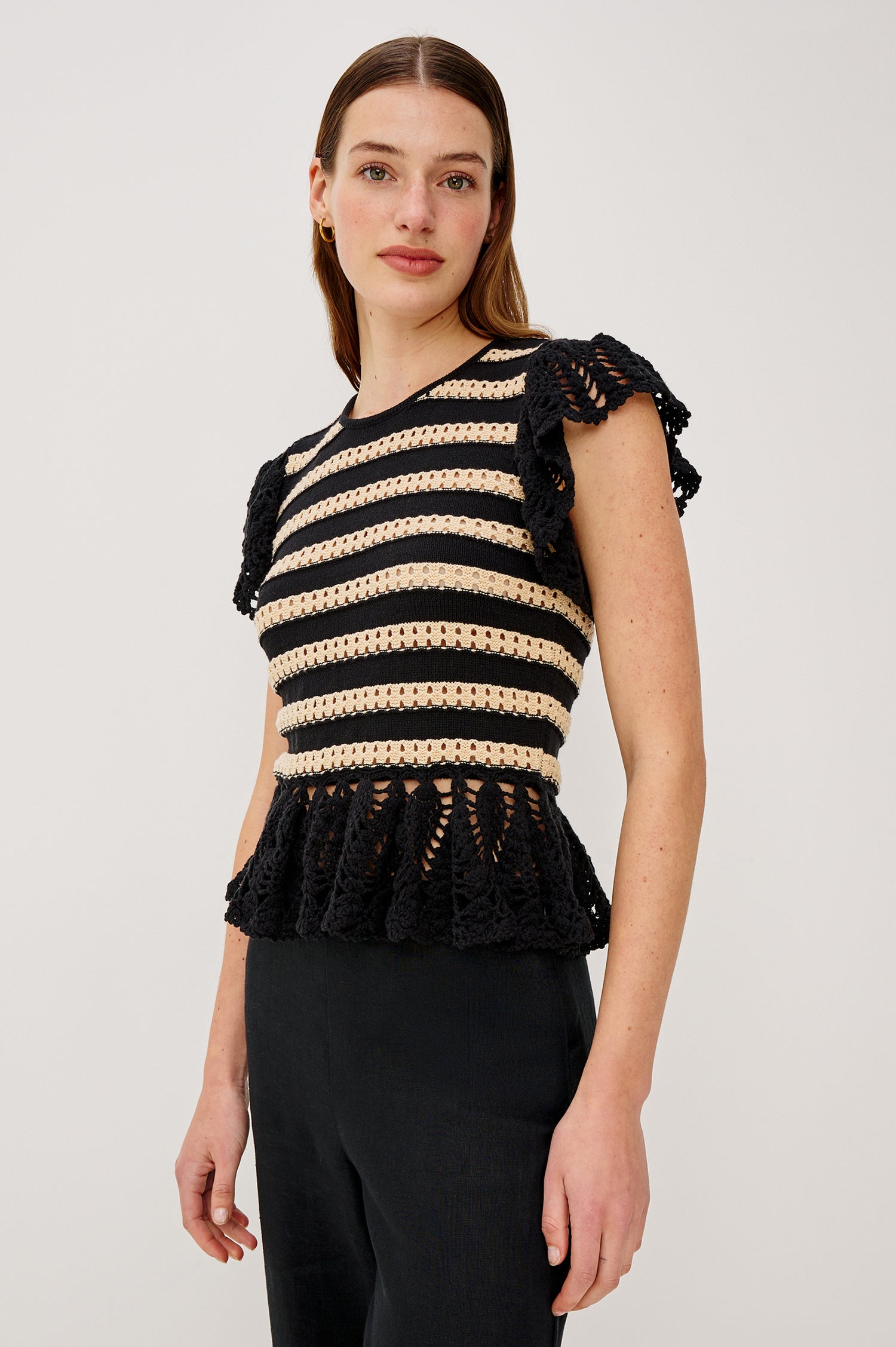 Coen Top in Cotton Blend Crochet With Crew Neckline Eyelet Detailing Flutter Sleeves Pepplum Hem and Back Keyhole With Adjustable Ties in Black Oat Stripe Colorway - Upper Body Front View Featured on Model