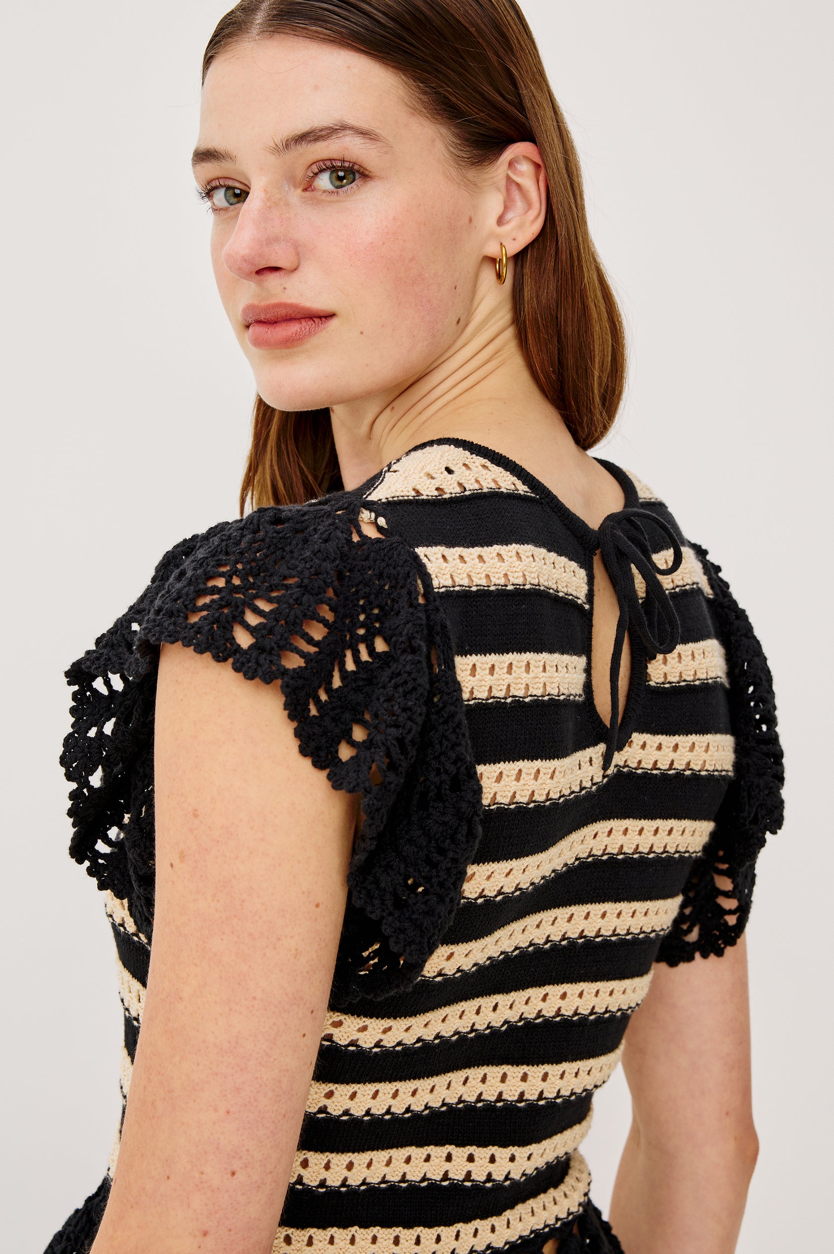 Coen Top in Cotton Blend Crochet With Crew Neckline Eyelet Detailing Flutter Sleeves Pepplum Hem and Back Keyhole With Adjustable Ties in Black Oat Stripe Colorway - Upper Body Back View Featured on Model