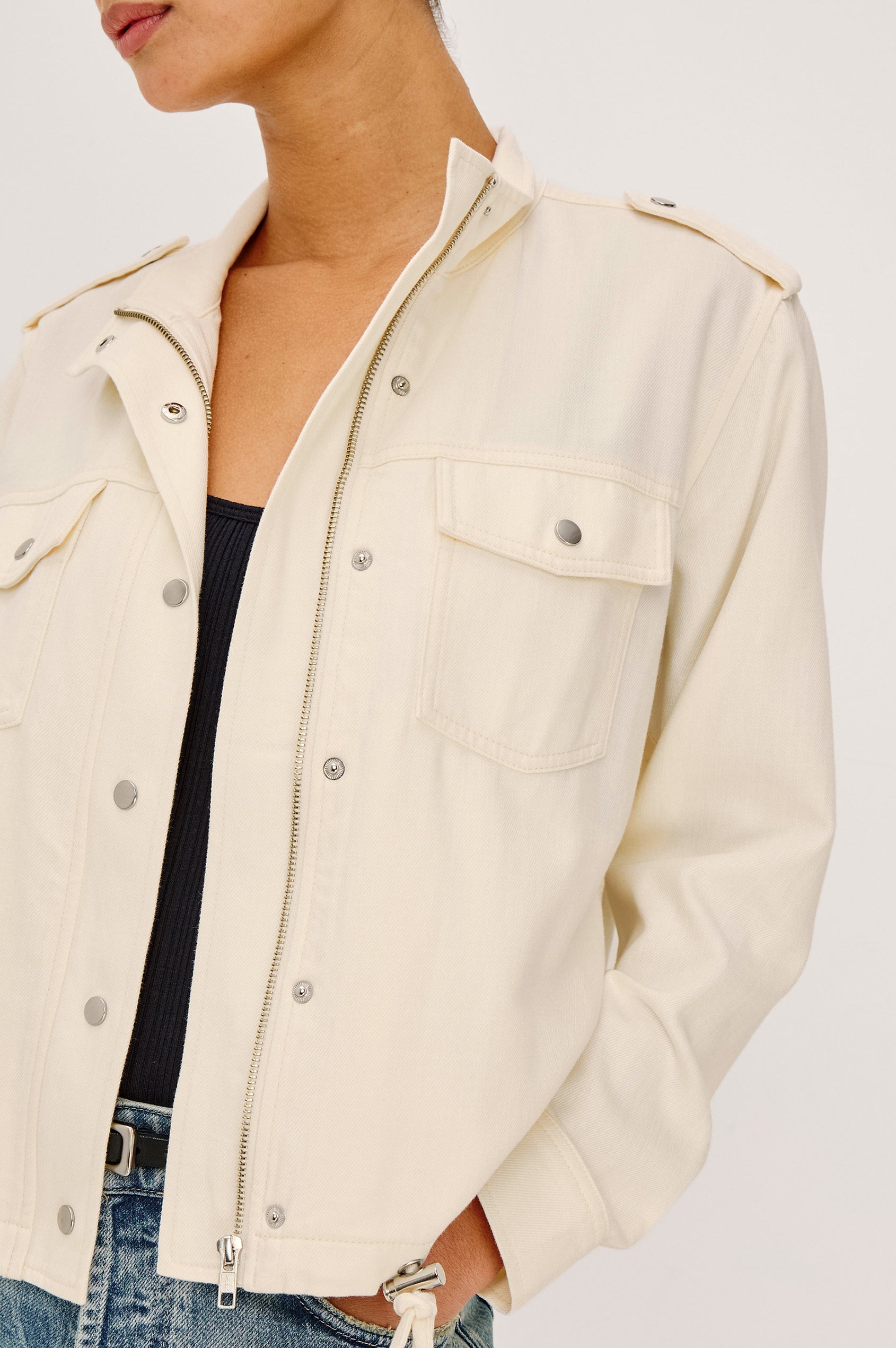 Collins Miitary Inspired Jacket With Shoulder Epaluettes, Stand Collar, Front Snap Buttons, Double Chest Pockets, Long Sleeves in Ivory Colorway - Upper Body Close Up Front View Featuered on Model