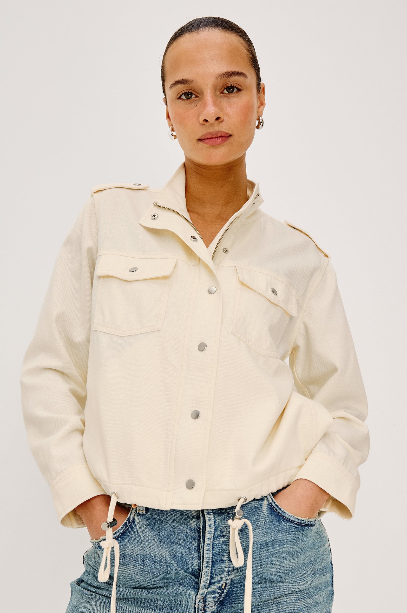 Collins Miitary Inspired Jacket With Shoulder Epaluettes, Stand Collar, Front Snap Buttons, Double Chest Pockets, Long Sleeves in Ivory Colorway - Upper Body Front View Featuered on Model