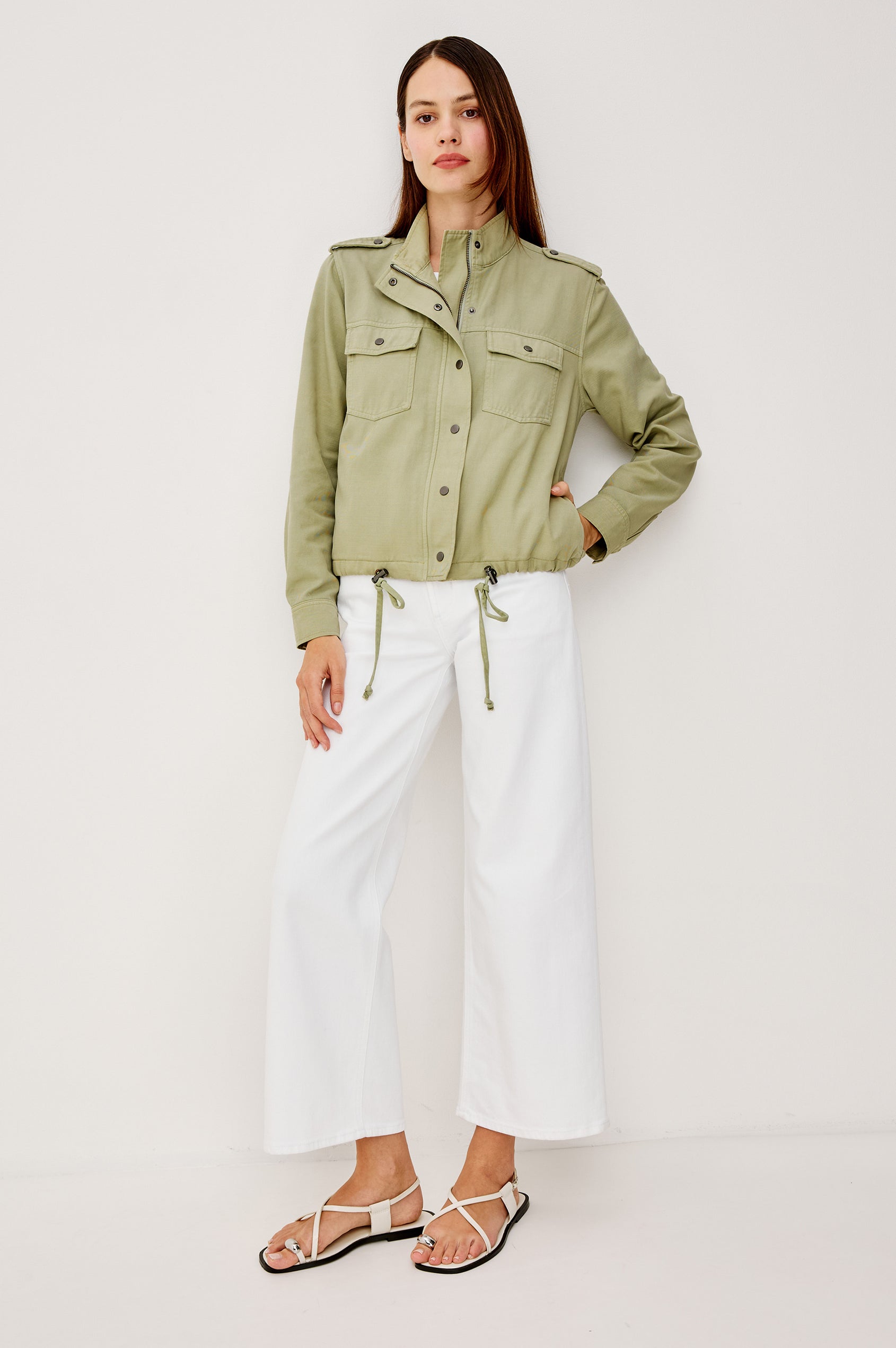 Collins Miitary Inspired Jacket With Shoulder Epaluettes Stand Collar Front Snap Buttons Double Chest Pockets Long Sleeves in Vintage Sage Colorway - Full Body View Featured on Model