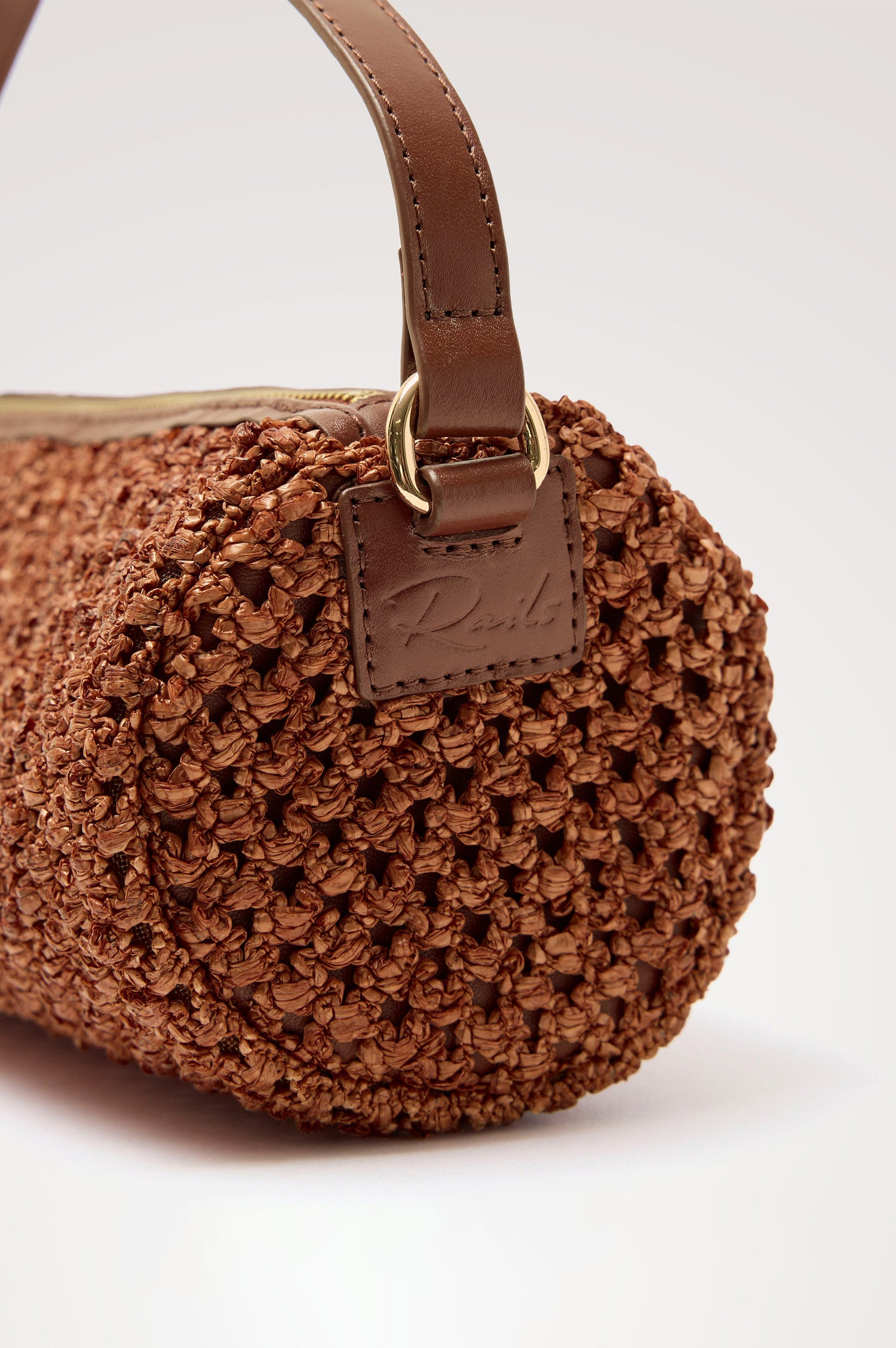 Como Mini Barrel Bag in Woven Raffia With Top Strap, Removable and Adjustable Crossbody Strap, and Top Zip in Cognac Raffia Colorway - Top View Featured