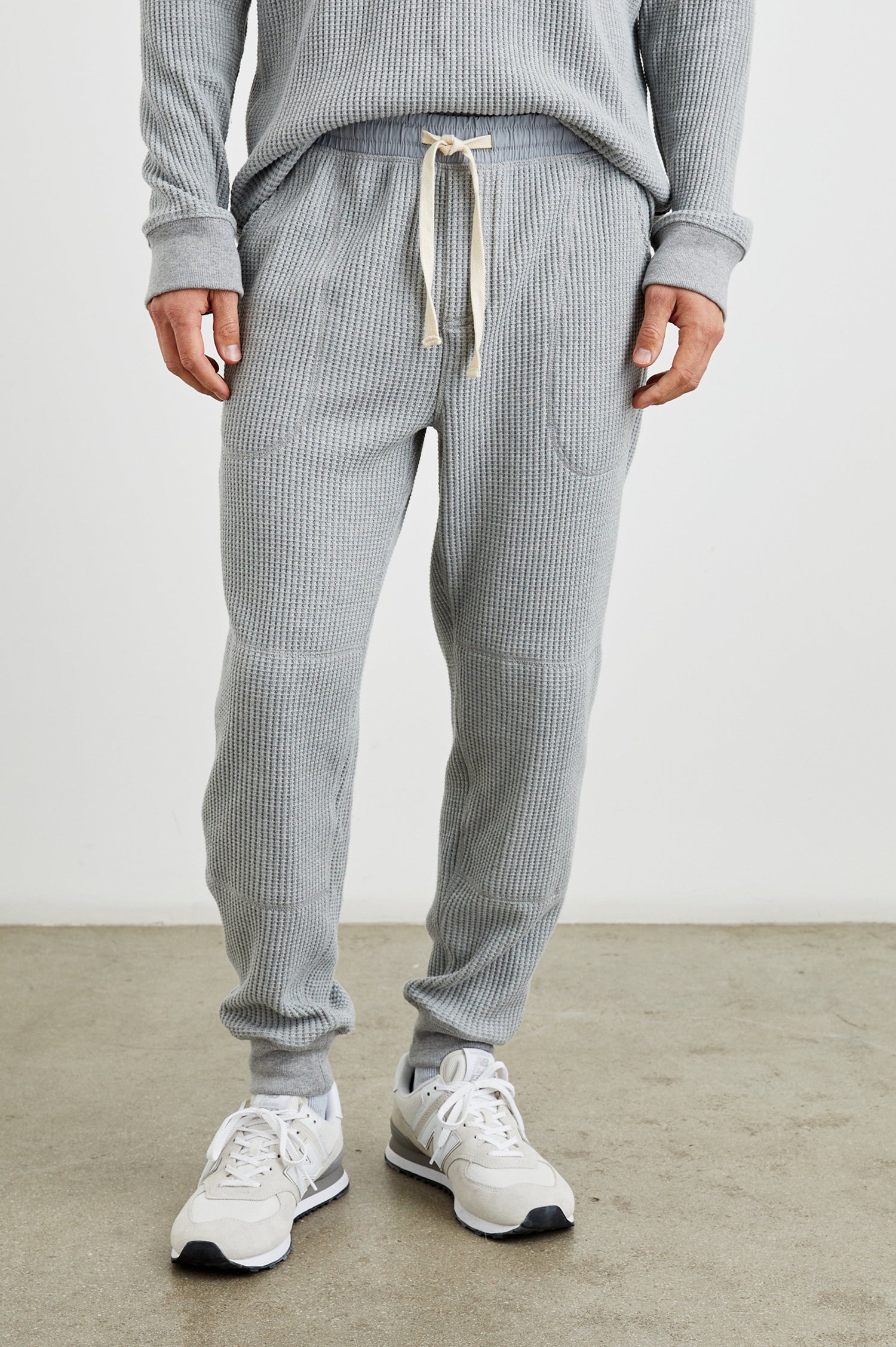 Cooper Waffle Thermal Pants with an Elastic Drawstring Waist, Two Teardrop Front Pockets, Two Back Welt Pockets, Reinforced Knee Patches and Elastic Cuffs in Heather Grey Colorway - Front View Featured on Model