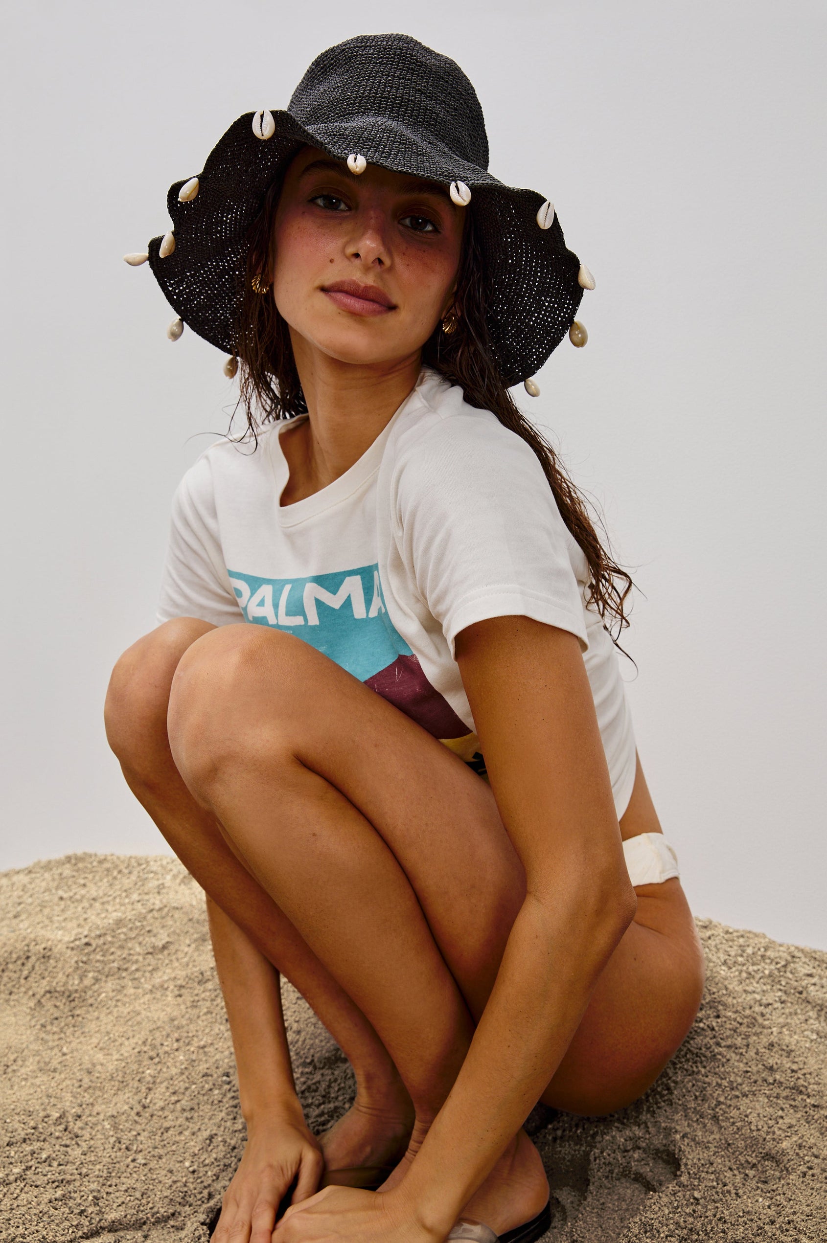 Crete Rattan Wide Brim Hat with Hanging Sea Shells at Edge in Black Colorway. Front View Shown on Model.