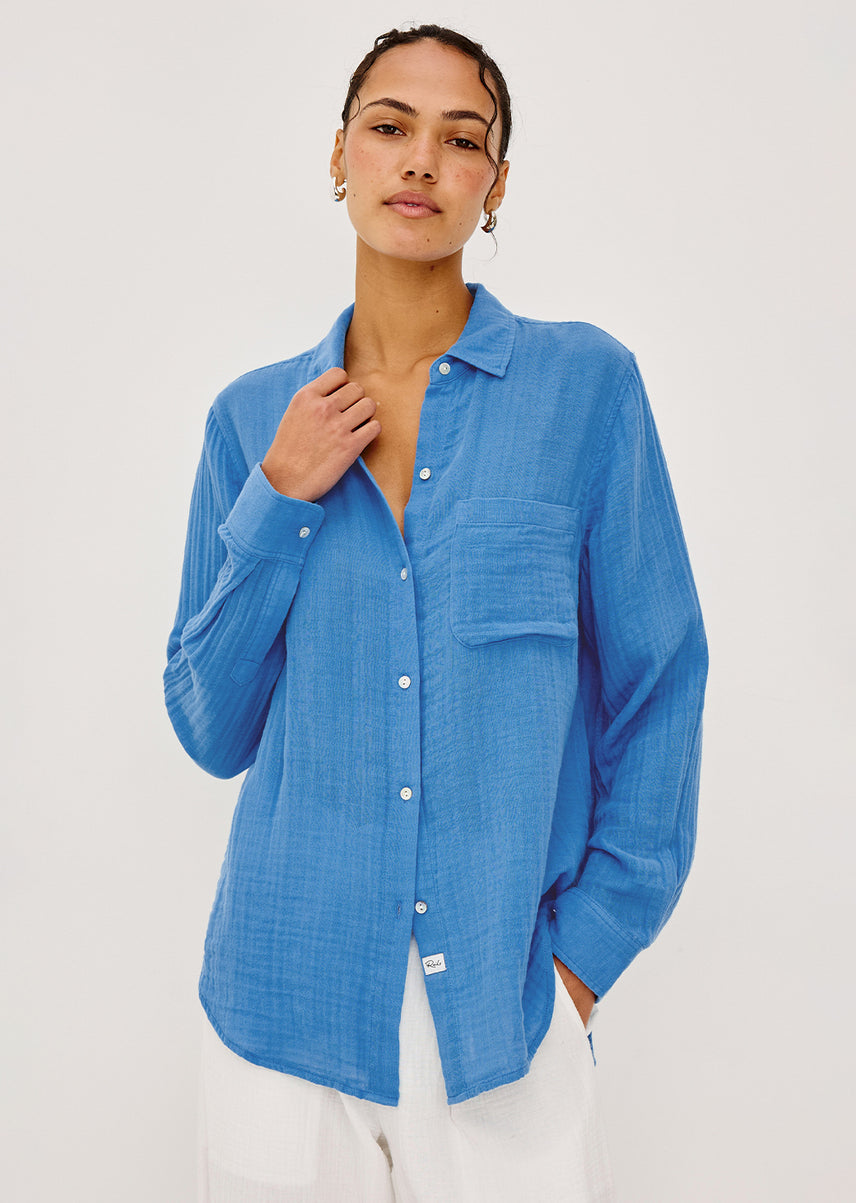 Woman wearing a blue button-up shirt against a white background