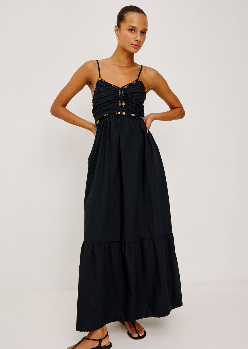 Woman wearing a black dress with gold accents on a white background
