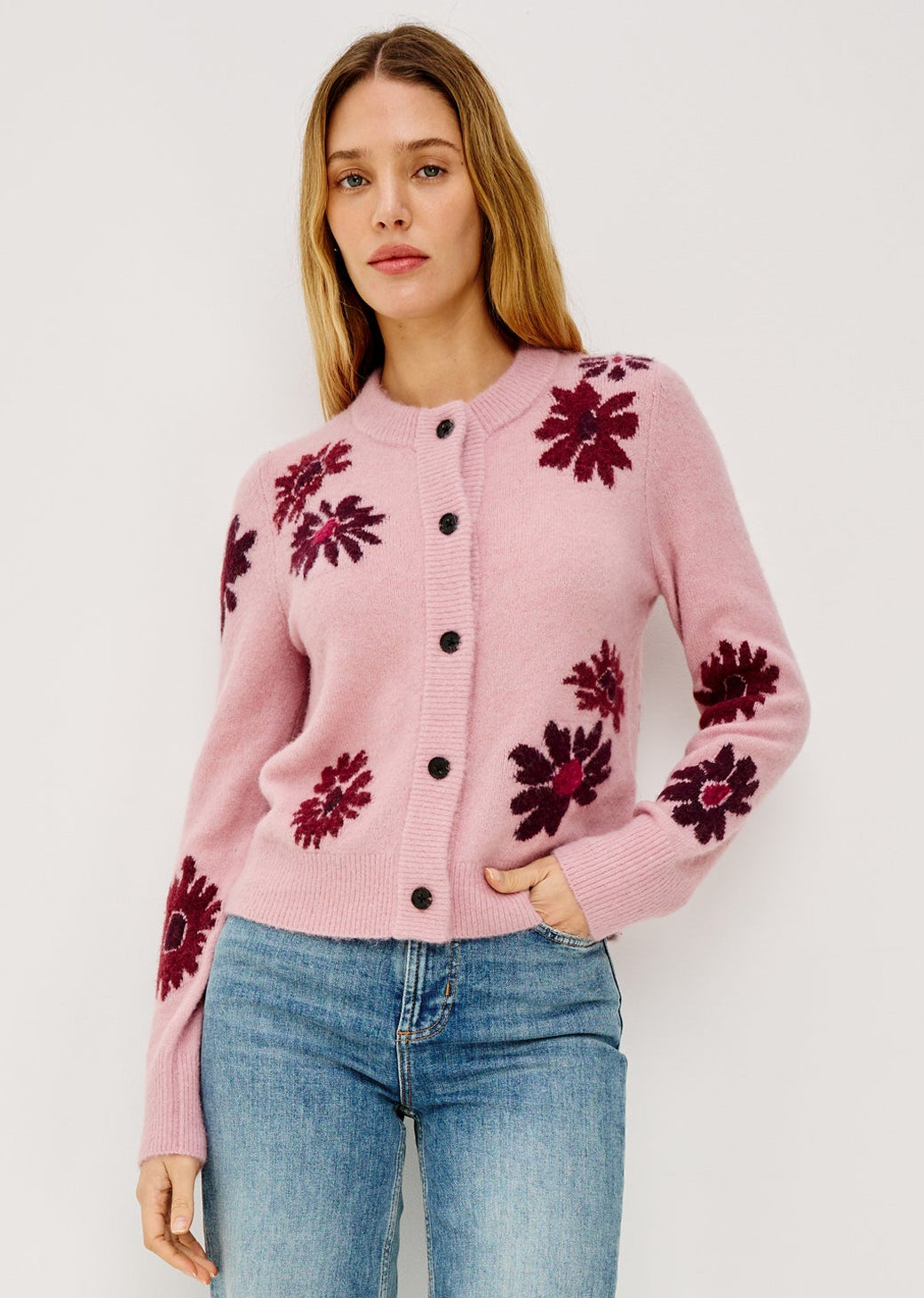 Woman wearing a pink cardigan with floral patterns on a white background