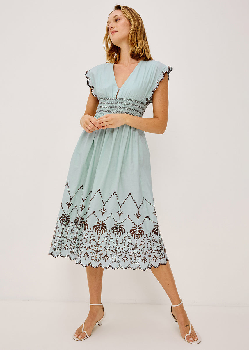 Woman wearing a light blue dress with lace details on a white background